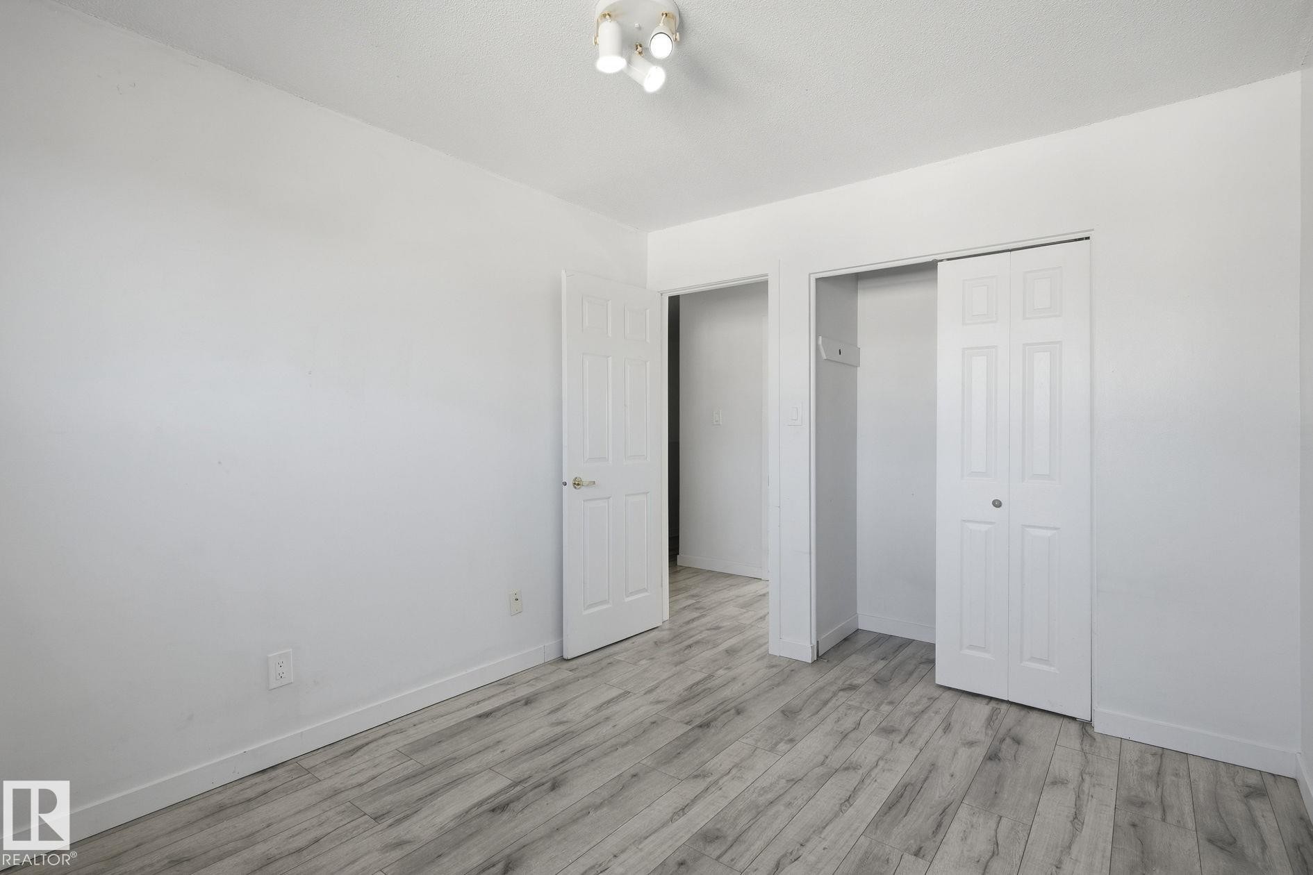 Wood-finish flooring, white walls, interior doors, bi-fold closet doors, and overhead track lighting - 164 Dickinsfield Court Nw, Edmonton, AB