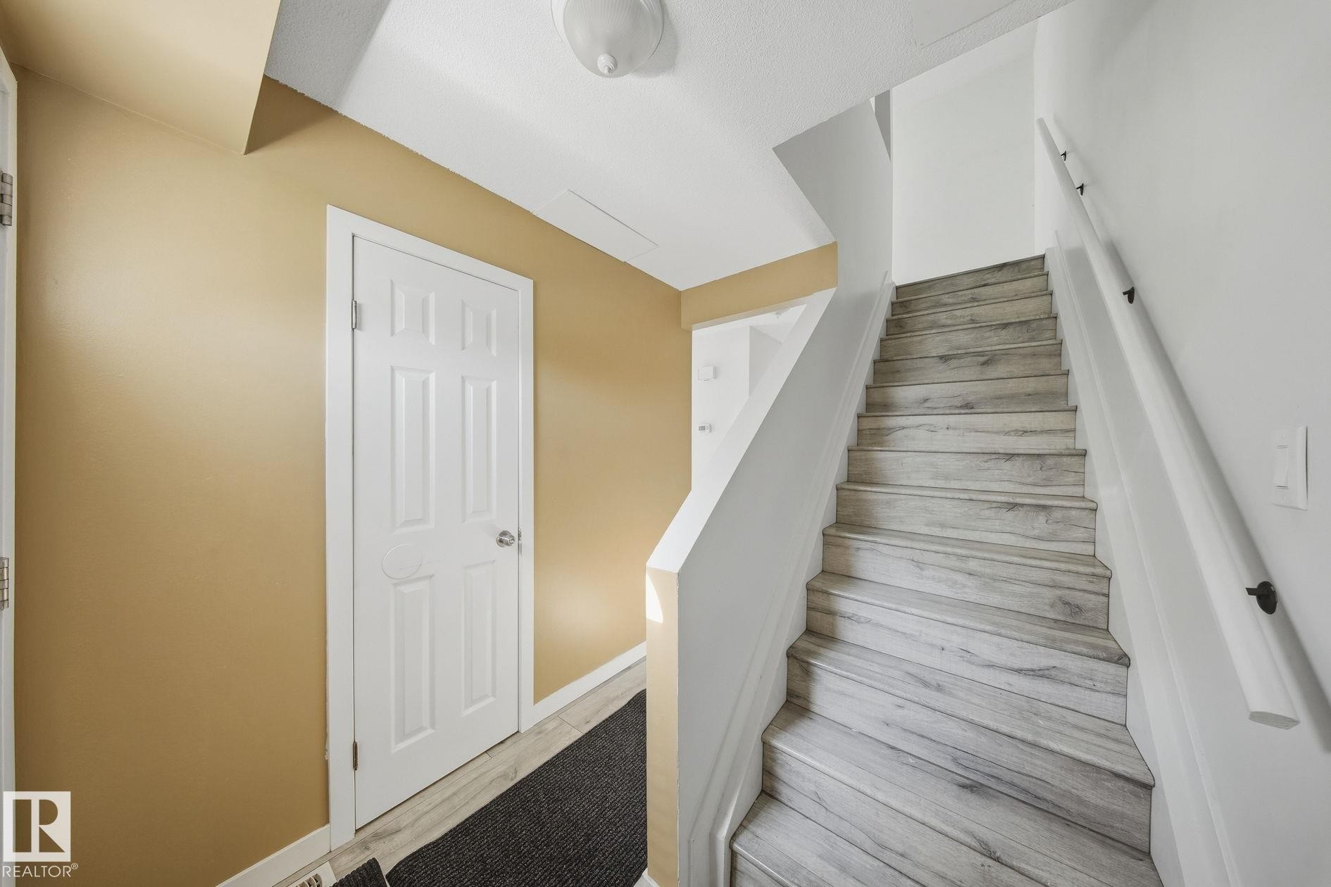 Staircase featuring wood-finish treads and a white handrail - 164 Dickinsfield Court Nw, Edmonton, AB