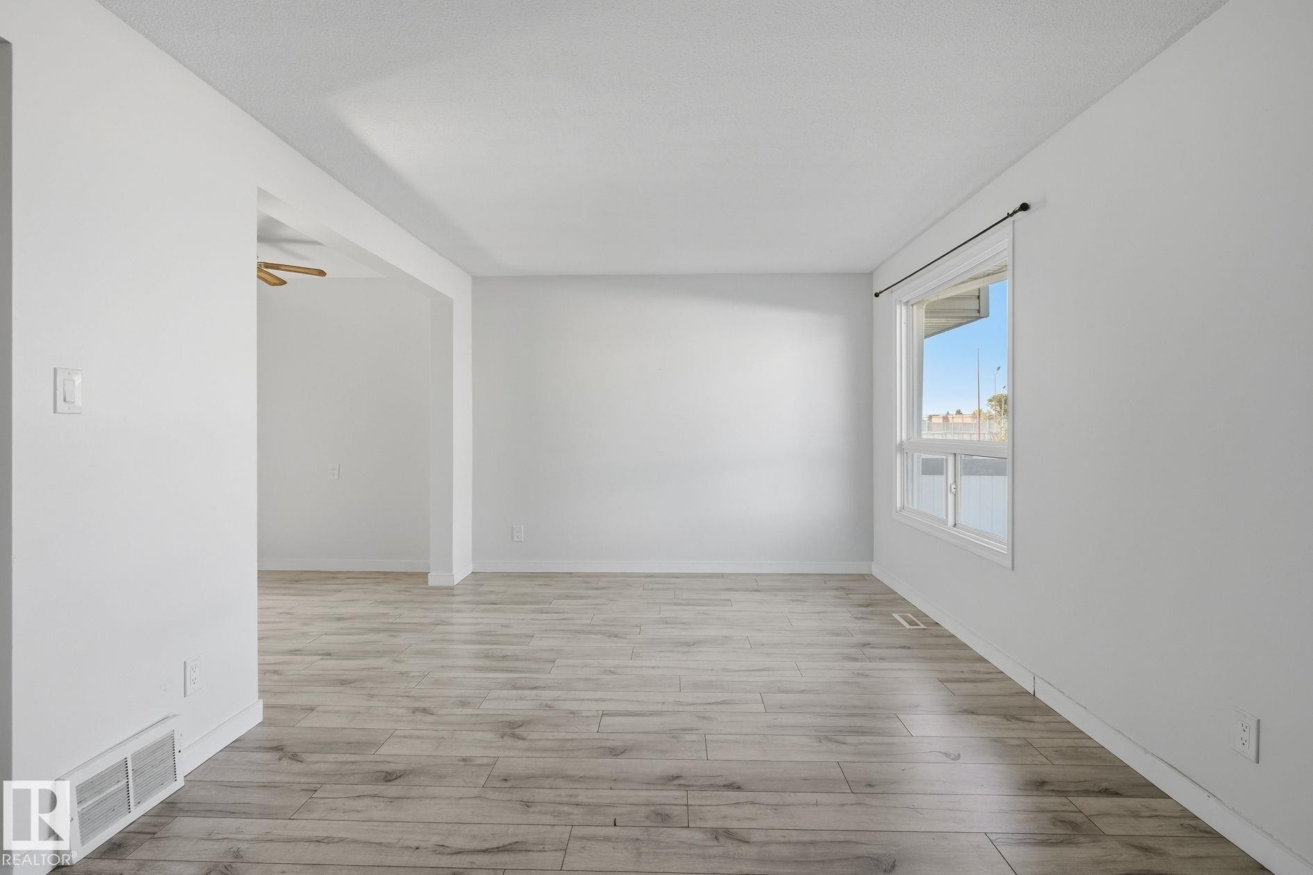 Spacious room featuring wood-finish flooring and white walls - 164 Dickinsfield Court Nw, Edmonton, AB