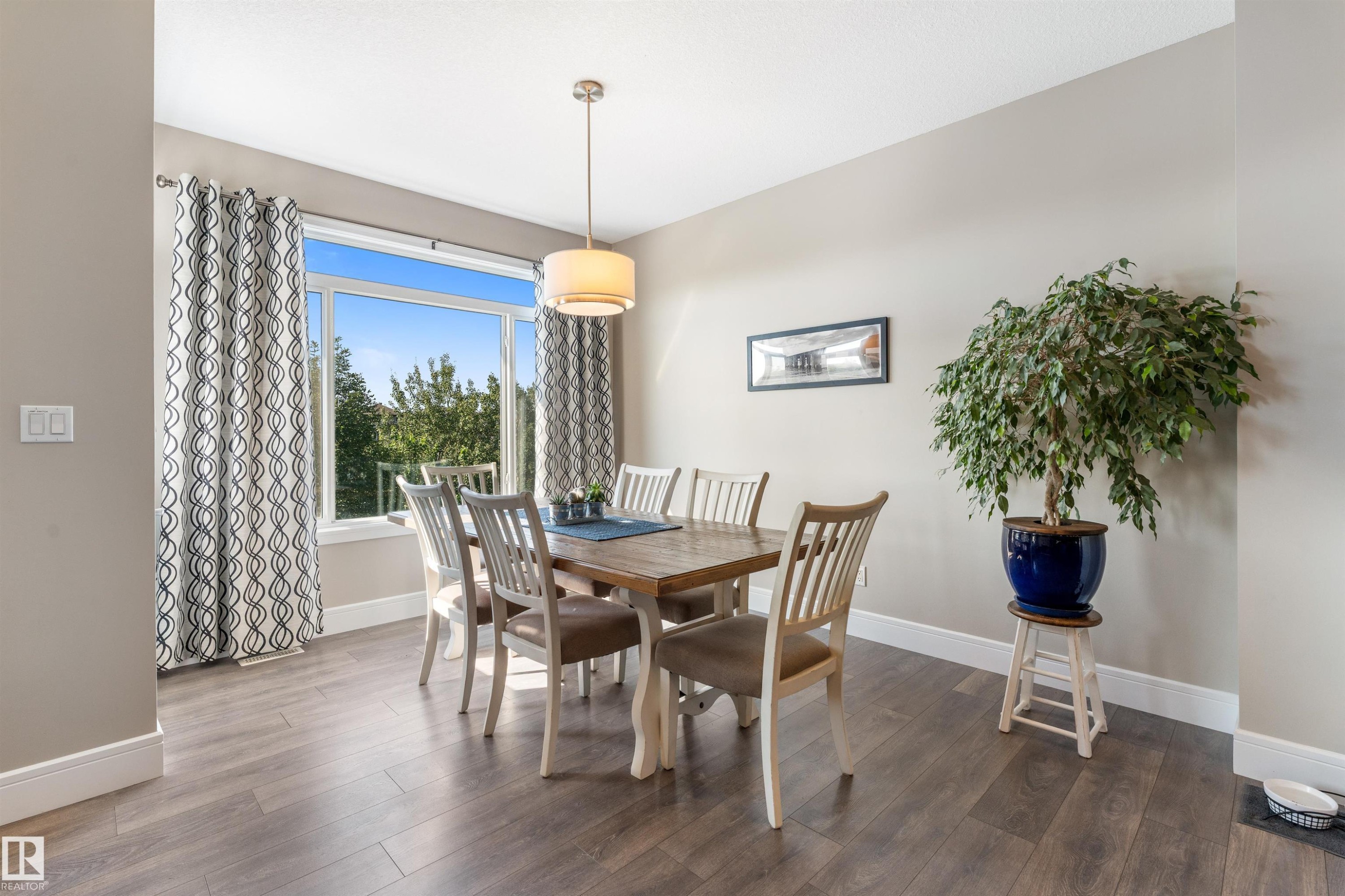 Expansive window with bright natural light, wood-finish flooring, recessed lighting, and a drum pendant fixture - 3334 Parker Loop Sw, Edmonton, AB