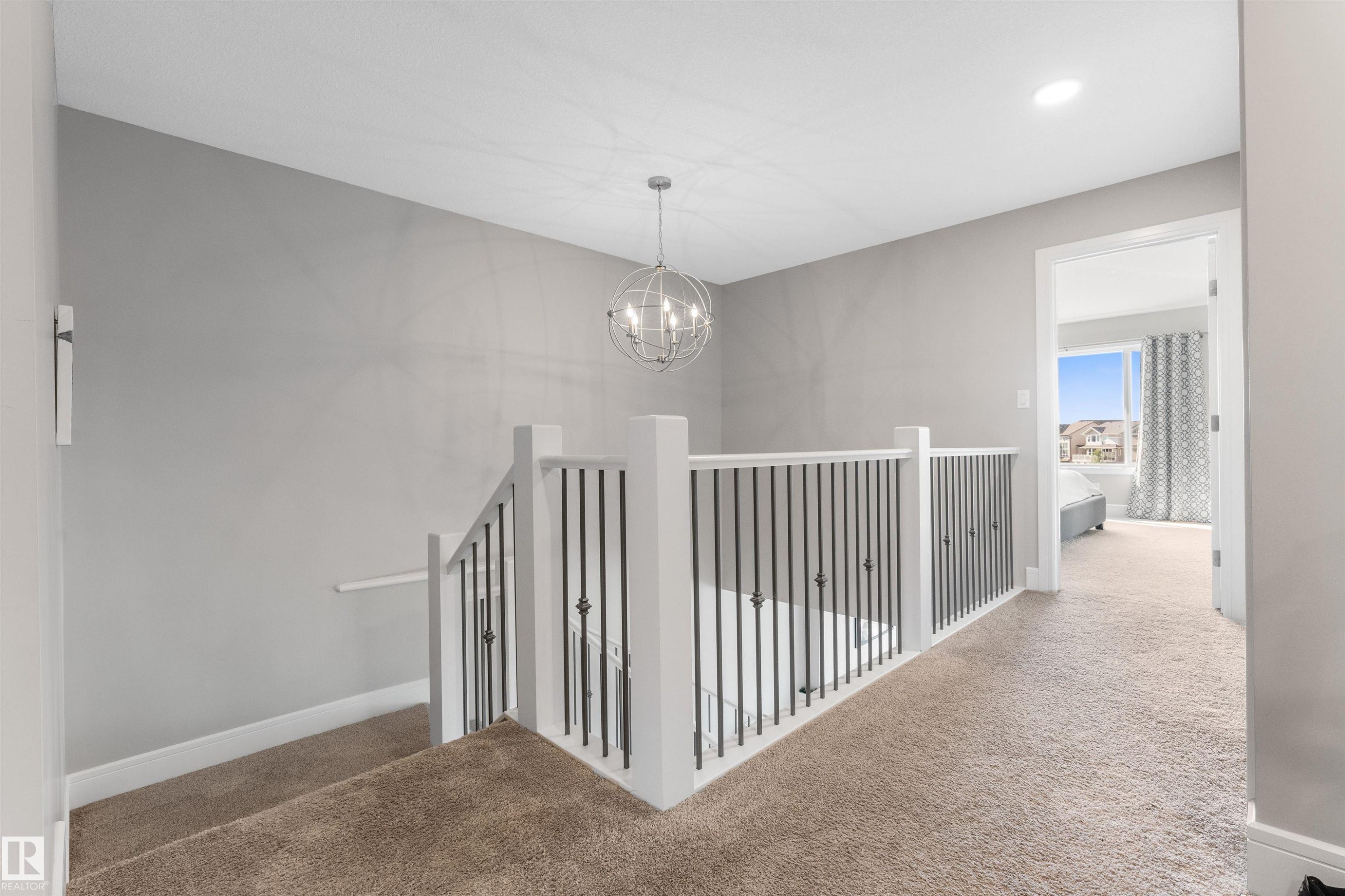 Staircase featuring white newel posts and balusters, dark iron spindles, and brown carpeted treads - 3334 Parker Loop Sw, Edmonton, AB