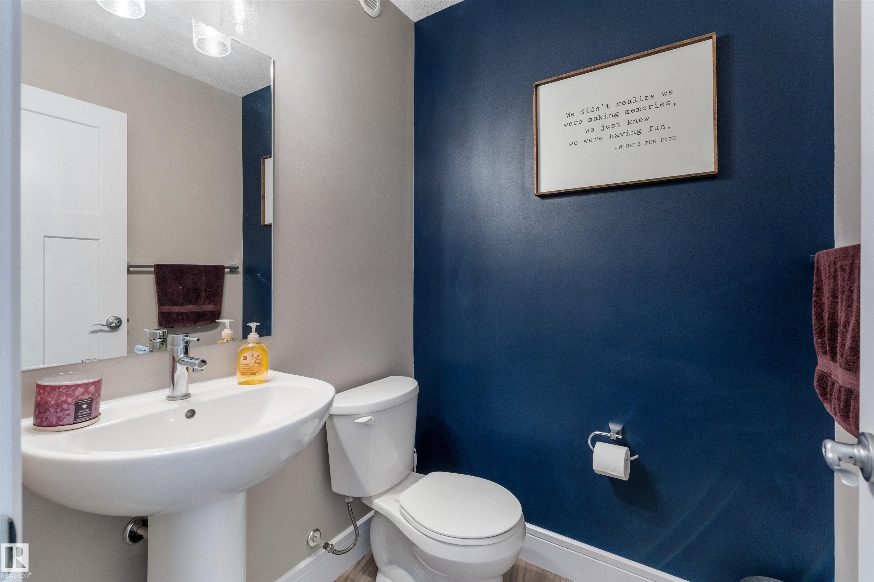Pedestal sink with chrome faucet, wall-mounted mirror, and vanity lighting - 3334 Parker Loop Sw, Edmonton, AB