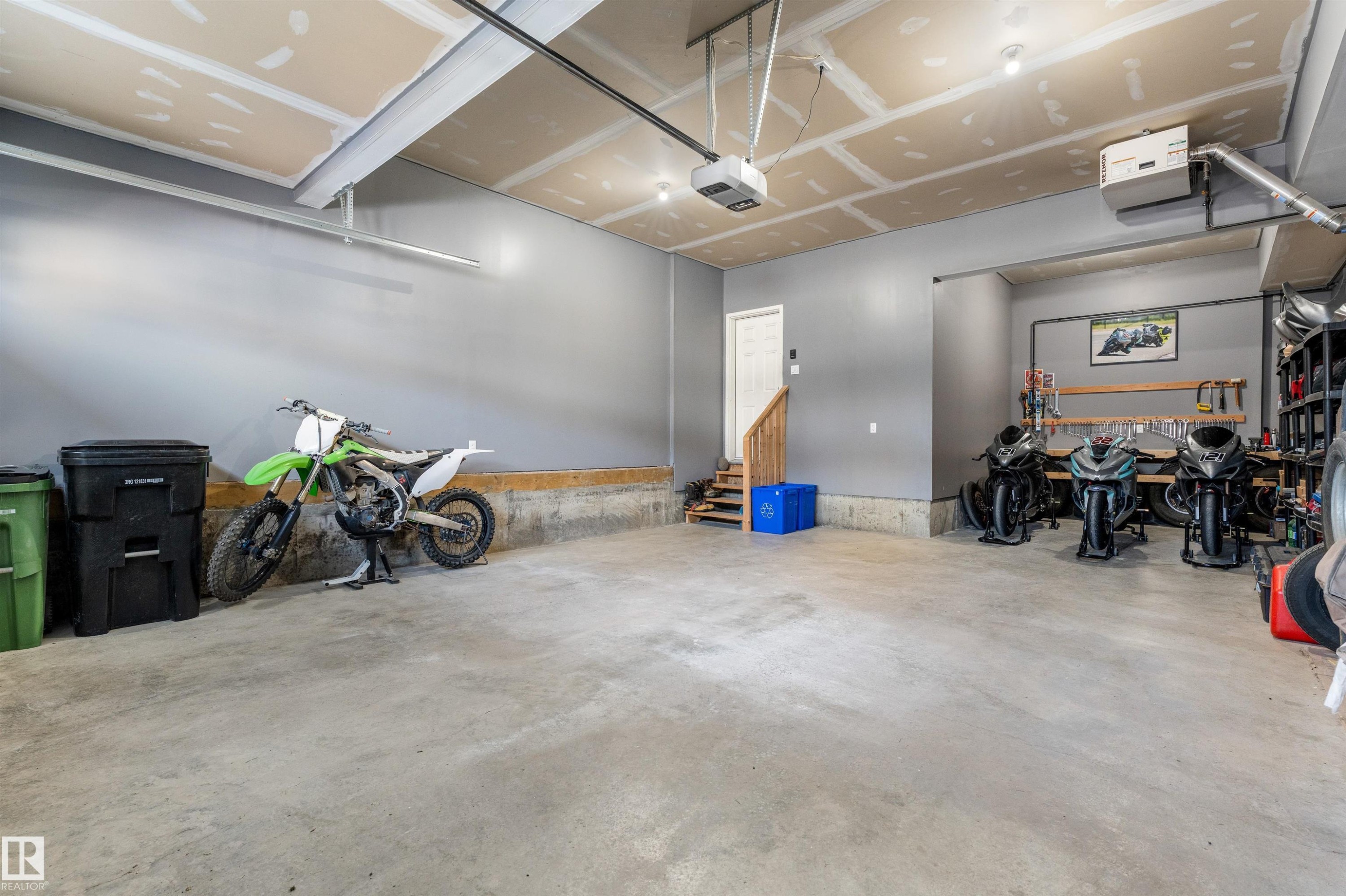 Concrete flooring, painted gray walls, built-in workbench with tool storage, built-in shelving, and exposed ceiling joists - 3334 Parker Loop Sw, Edmonton, AB