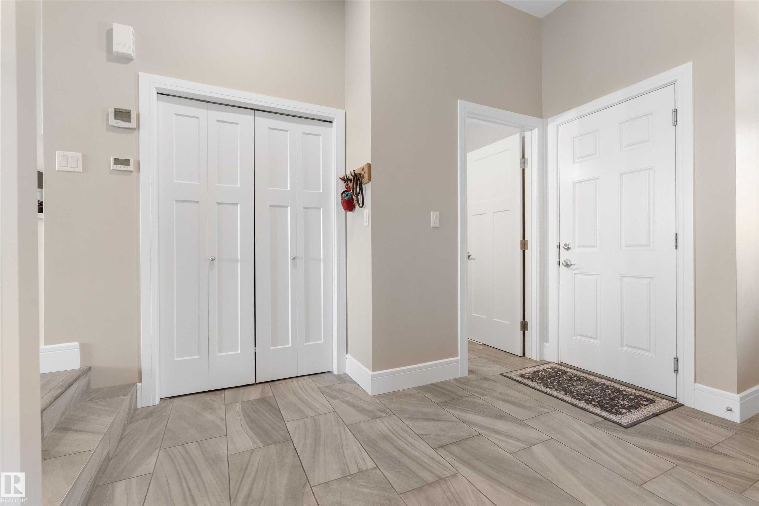 Entryway featuring light-toned walls, tile flooring, white panel doors, and a built-in closet - 3334 Parker Loop Sw, Edmonton, AB