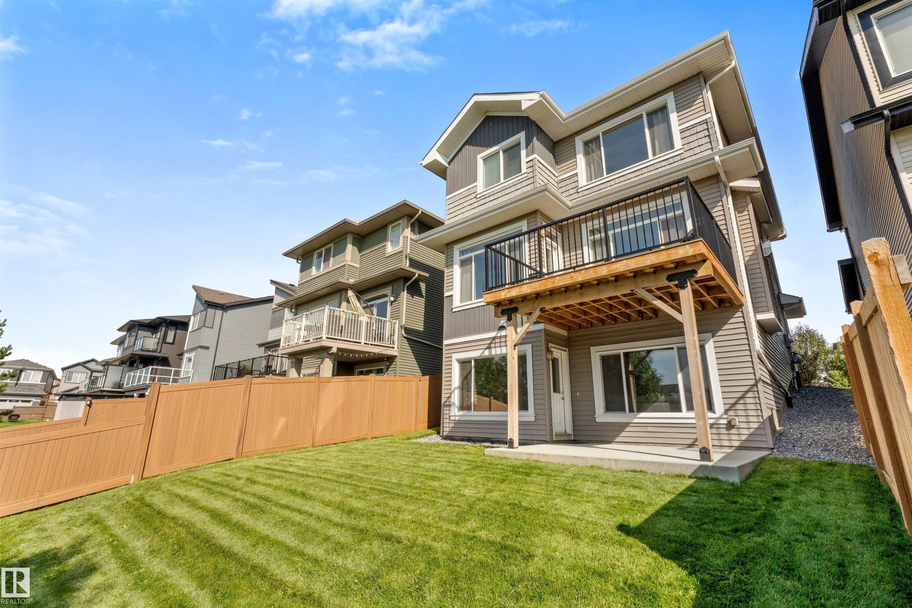 Expansive backyard with a manicured lawn, full privacy fencing, and a ground-level patio - 3334 Parker Loop Sw, Edmonton, AB