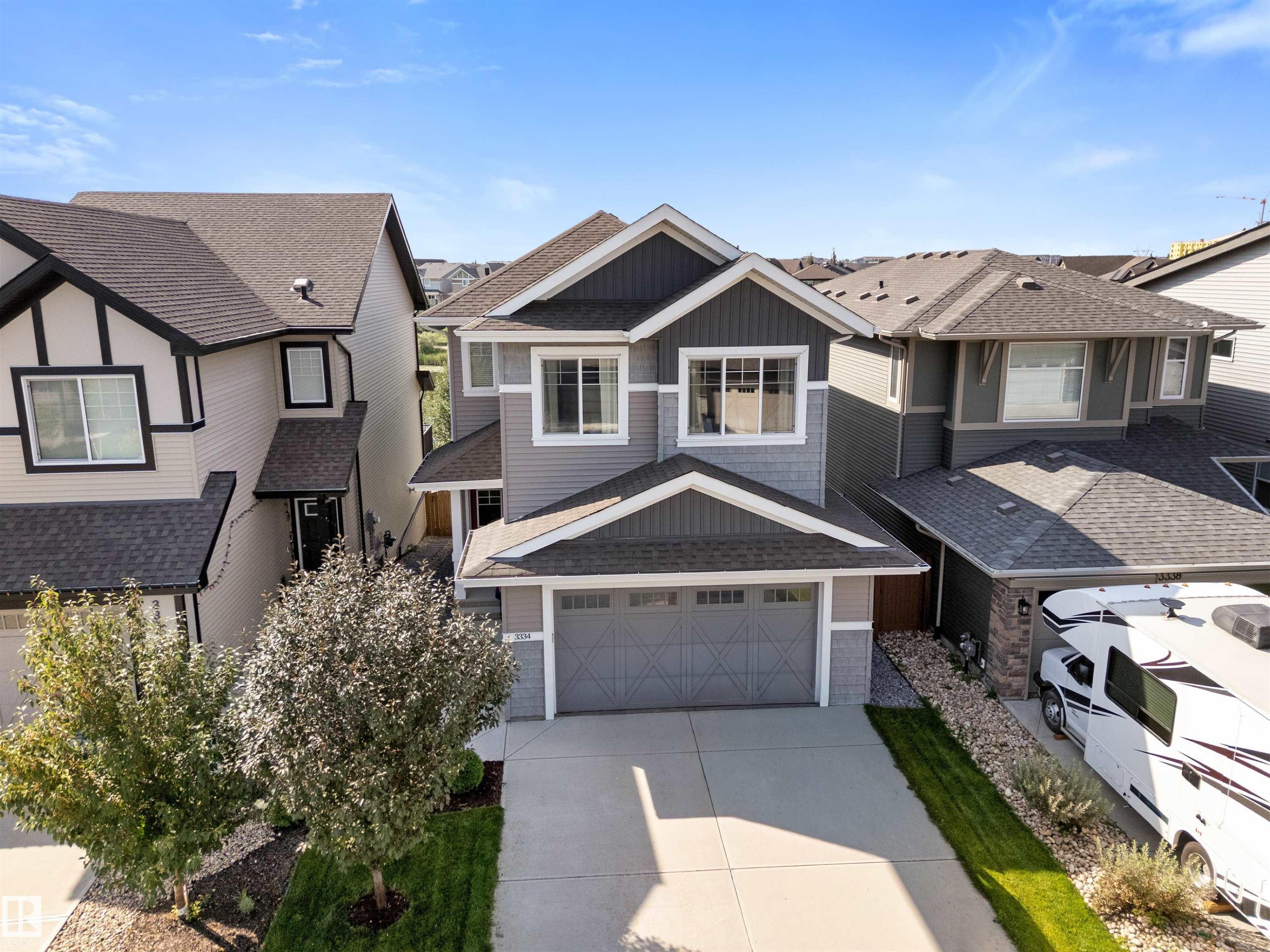 Two-story exterior with a two-car garage, gray siding, and a paved driveway - 3334 Parker Loop Sw, Edmonton, AB