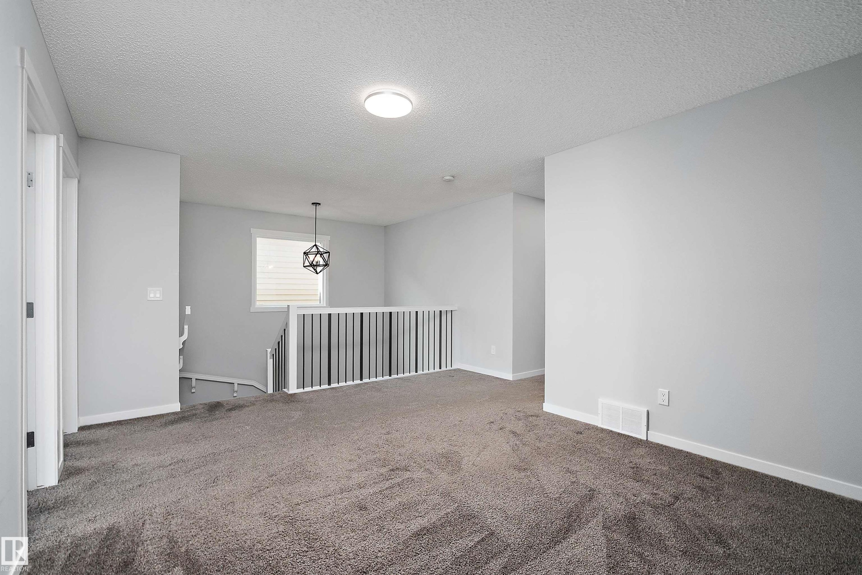 Spacious upper-level area with neutral gray wall paint, dark gray carpeting, a contemporary geometric light fixture, and white window blinds - 9227 223 Street Nw, Edmonton, AB