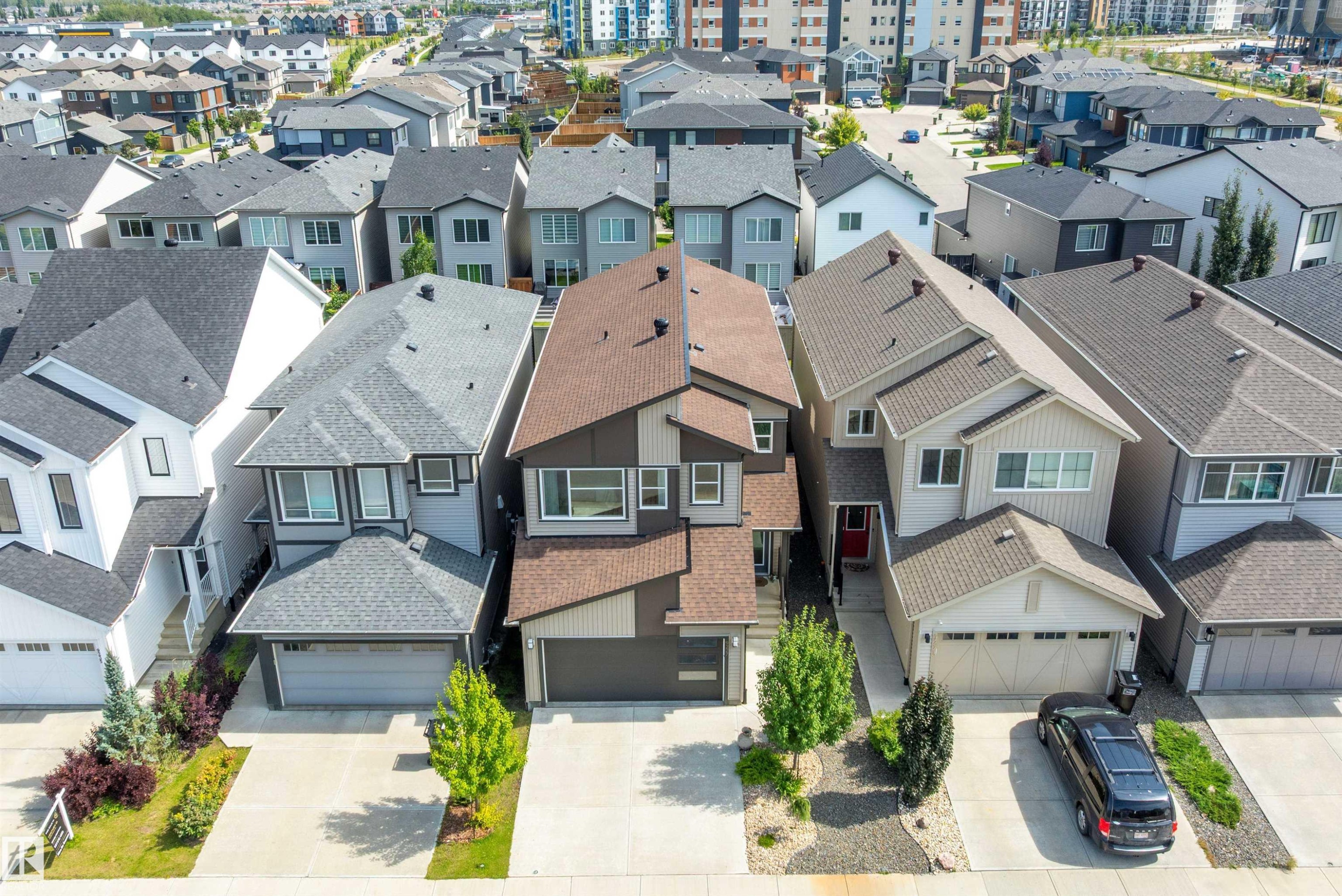Contemporary residential architecture featuring a brown and gray exterior, attached garage, and landscaped front yard - 9227 223 Street Nw, Edmonton, AB