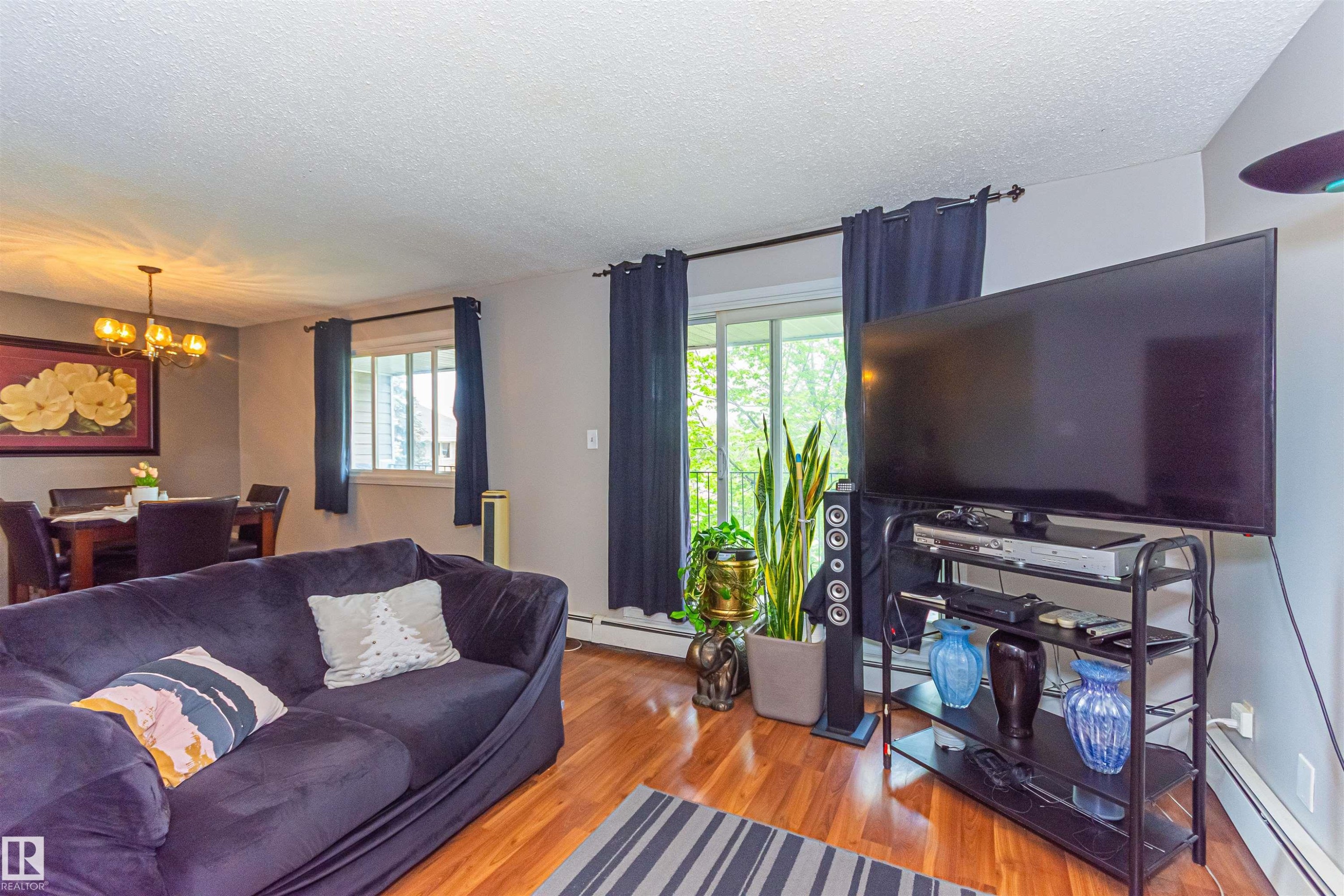 Wood-finish flooring, recessed lighting, and a modern chandelier illuminate the living and dining areas - #6 3819 76 St Nw, Edmonton, AB