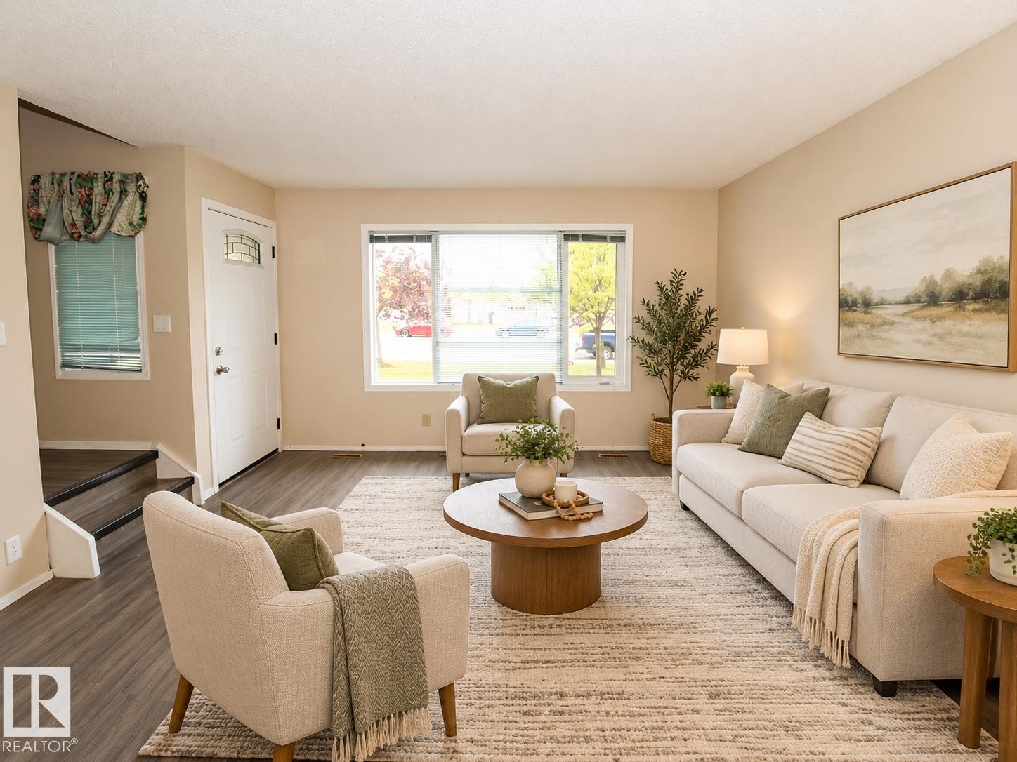 Spacious living area featuring wood-finish flooring, neutral wall tones, and a white entry door with a decorative glass insert - 11393 22 Avenue Nw, Edmonton, AB