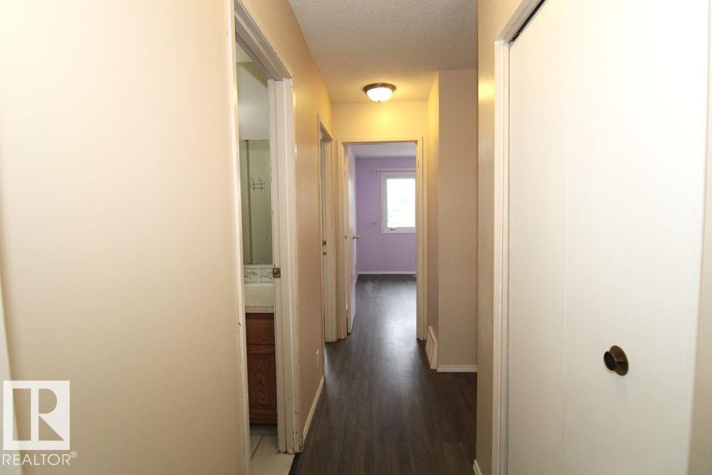 Hallway with wood-finish flooring, flush mount lighting, and white interior doors - 11393 22 Avenue Nw, Edmonton, AB