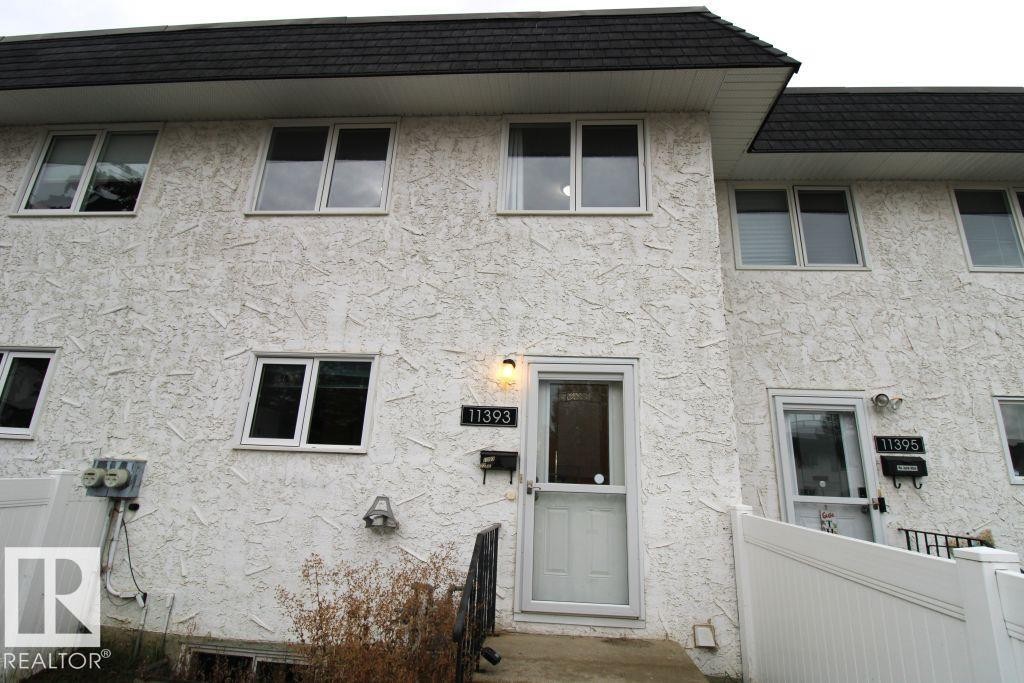 Stucco exterior with multiple windows, black asphalt shingle roof, and white entry door - 11393 22 Avenue Nw, Edmonton, AB