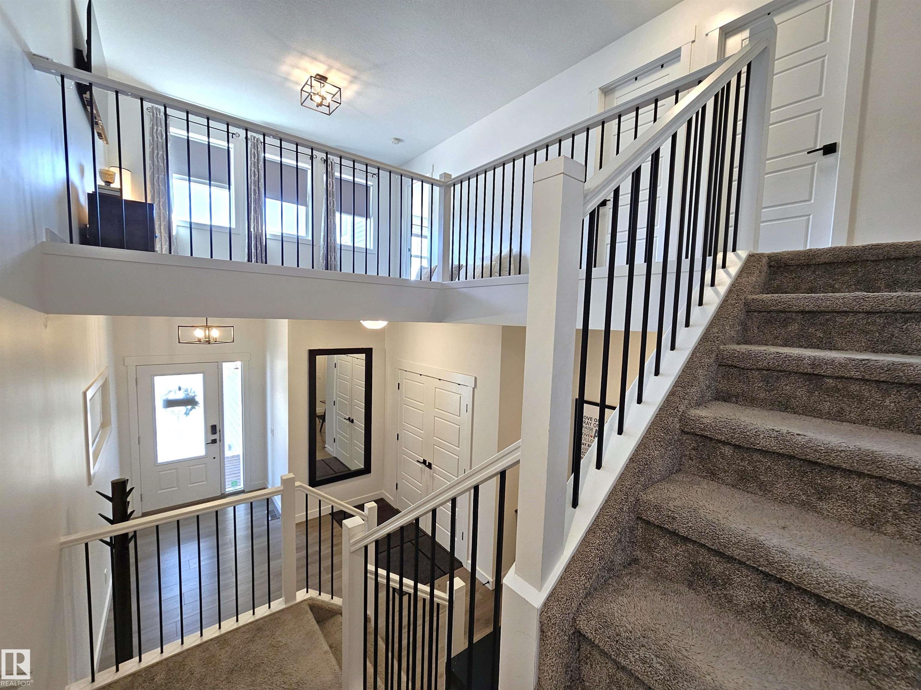 Multi-level interior featuring a carpeted staircase, white railing with black balusters, and a lofted area - 40 Jamison Crescent, St. Albert, AB