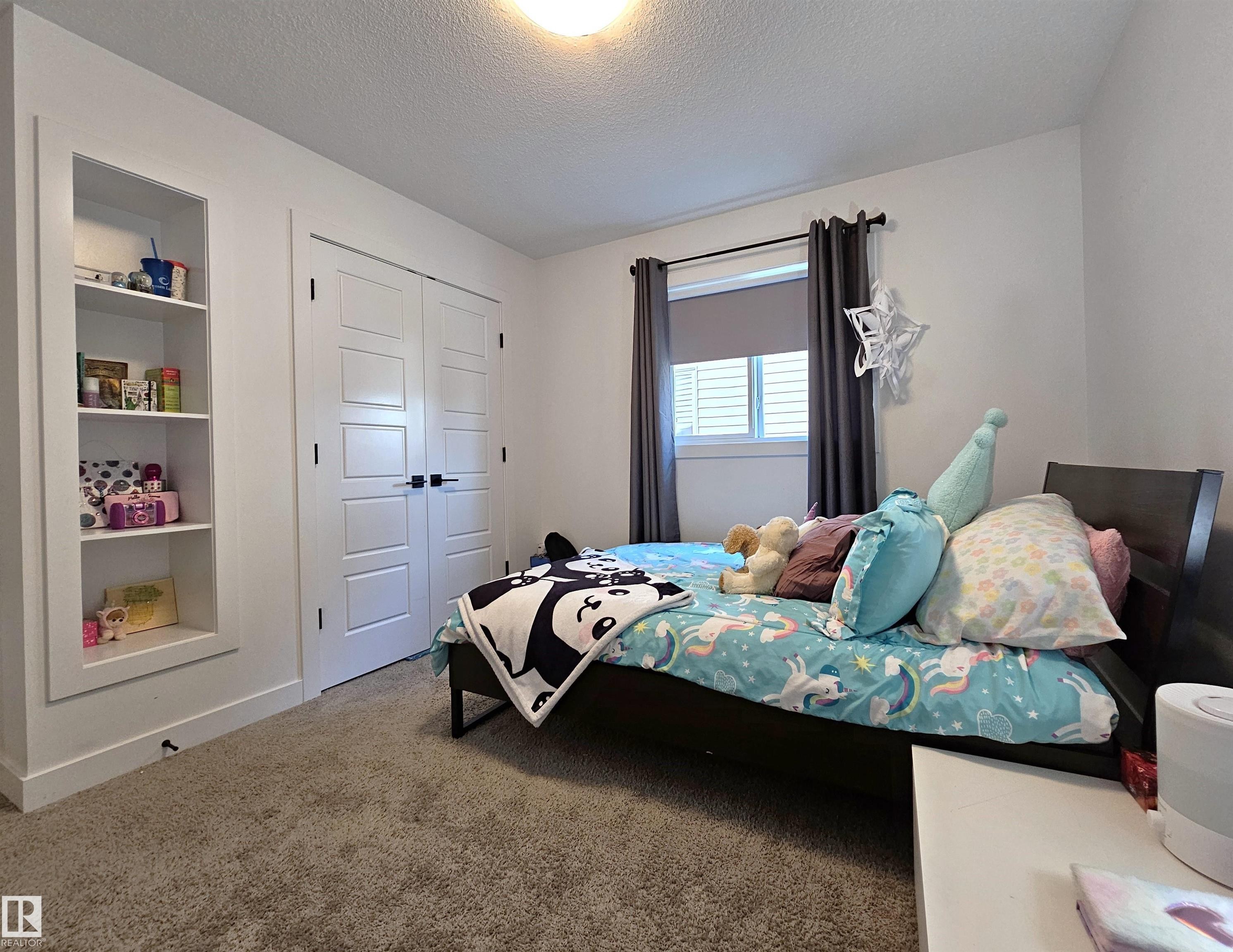 White built-in shelving, white paneled double doors with black hardware, and an overhead flush-mount light fixture - 40 Jamison Crescent, St. Albert, AB