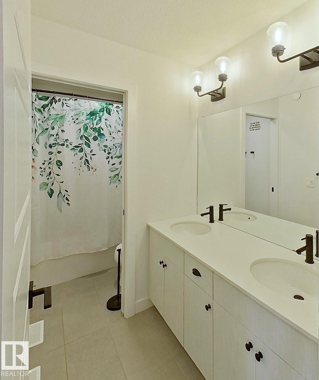 Dual vanity with integrated sinks, contemporary wall-mounted light fixtures, tile flooring, and white paneled door - 40 Jamison Crescent, St. Albert, AB