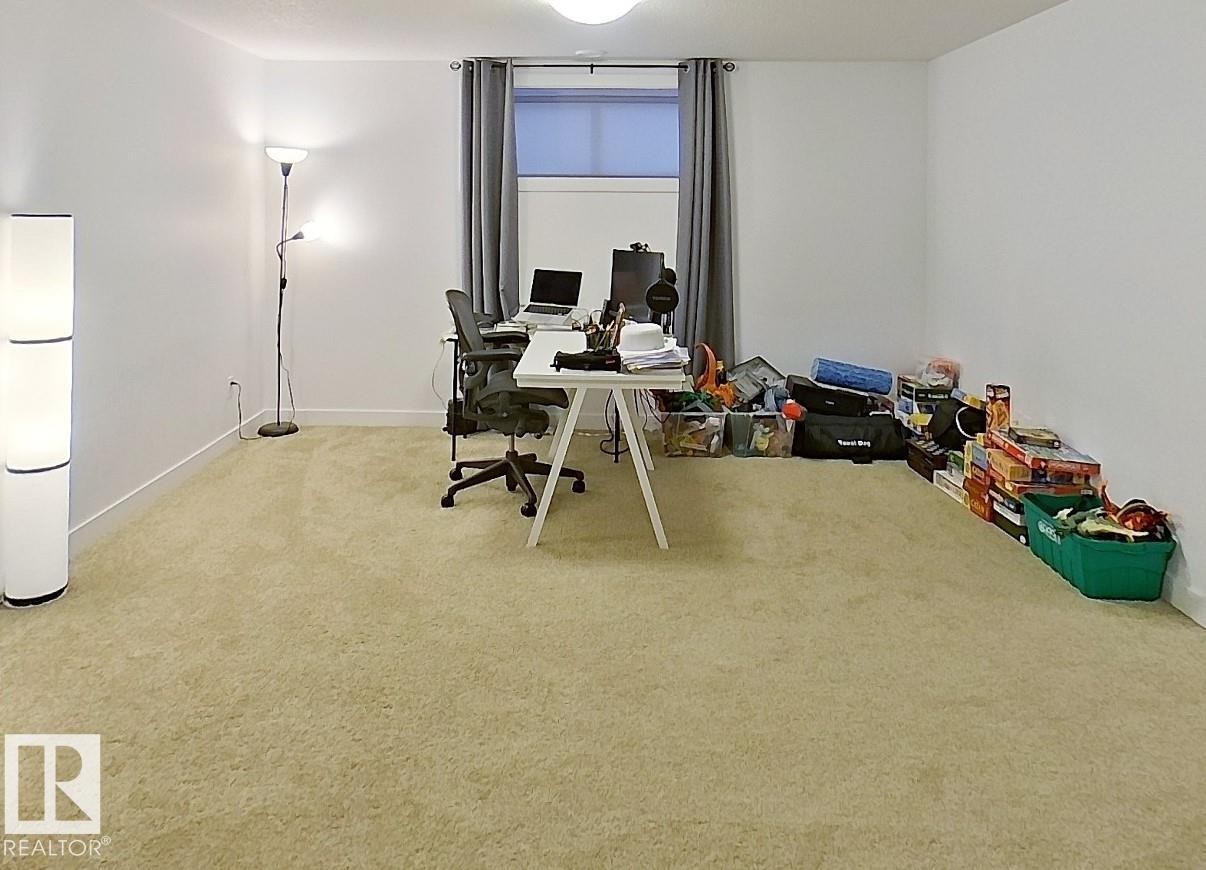 Carpeted room with a window, showcasing white walls and a ceiling light fixture - 40 Jamison Crescent, St. Albert, AB