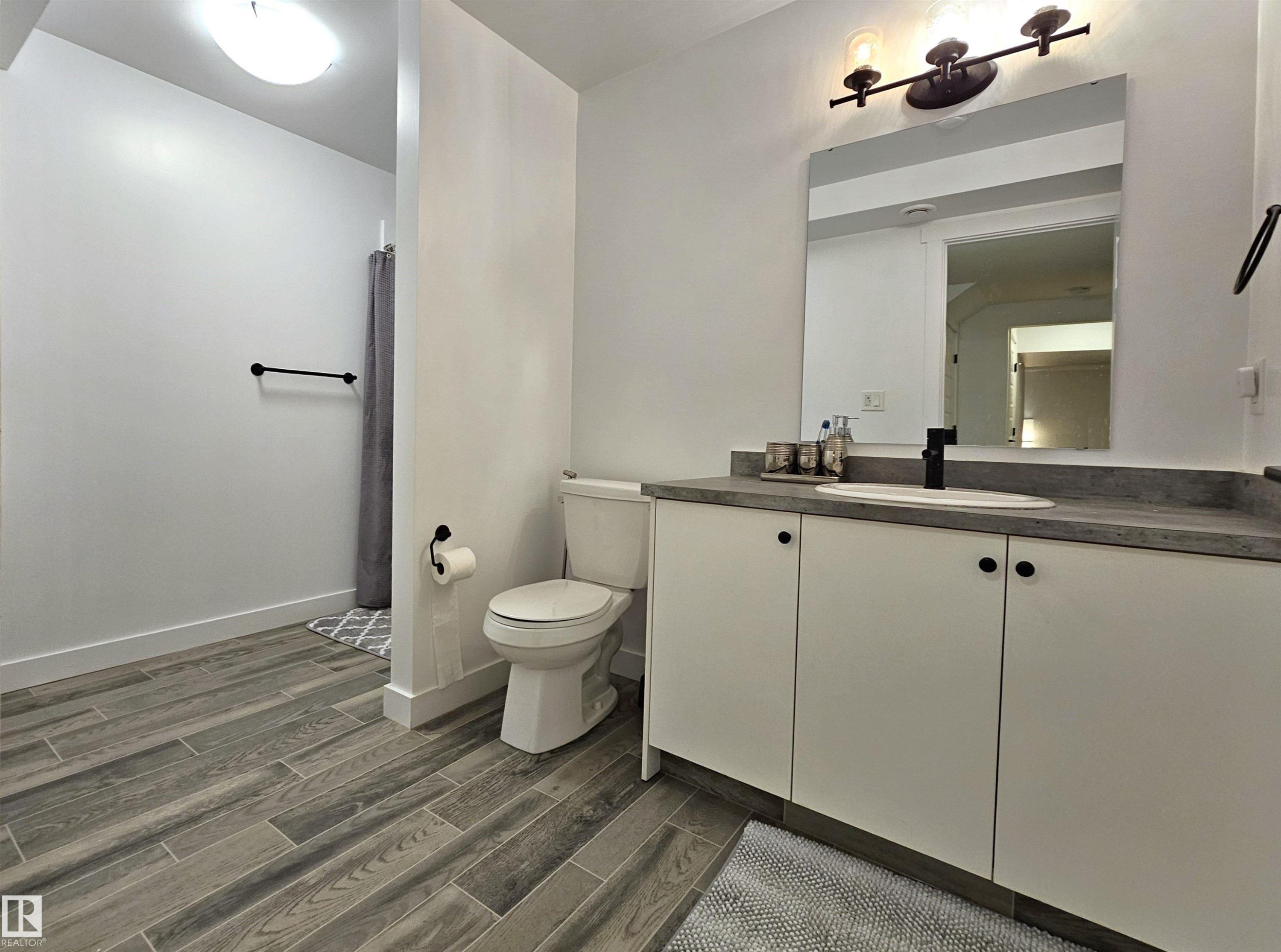 Vanity with white cabinetry, a flat-panel mirror, and a three-light fixture - 40 Jamison Crescent, St. Albert, AB