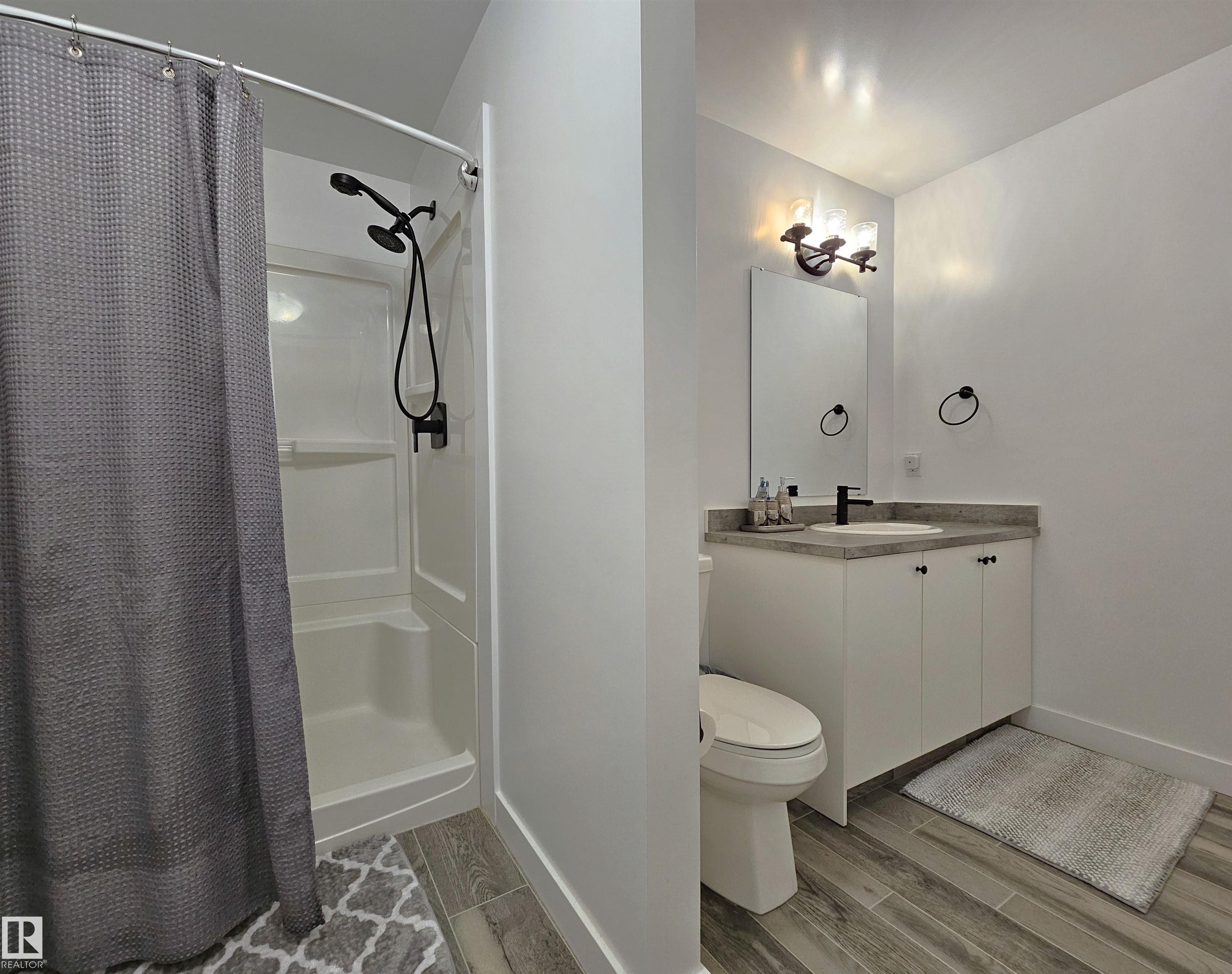 Contemporary bathroom featuring wood-finish tile flooring and a white vanity with a light-toned countertop - 40 Jamison Crescent, St. Albert, AB