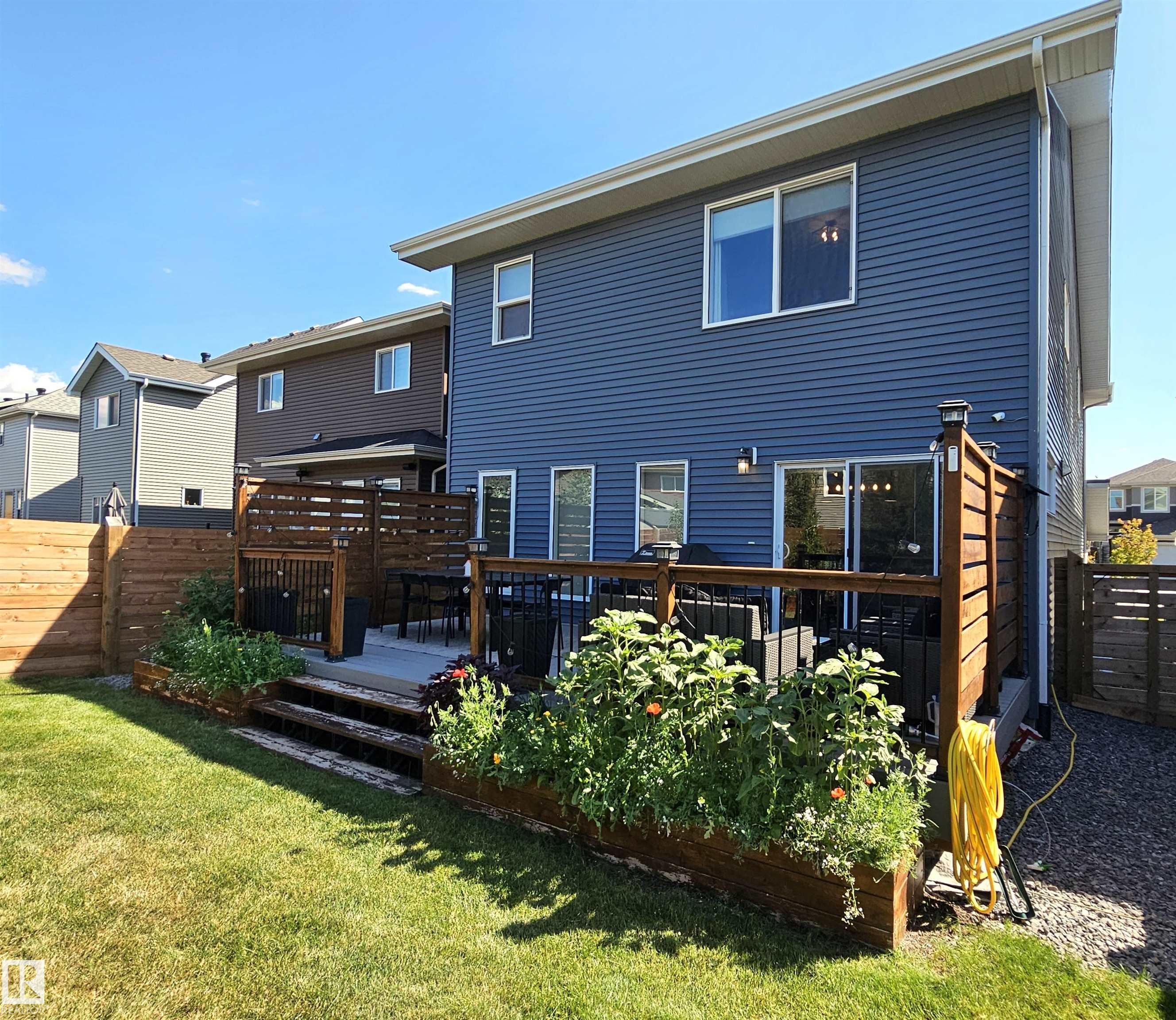Expansive backyard featuring a manicured lawn, multi-level wood deck, and built-in planters - 40 Jamison Crescent, St. Albert, AB