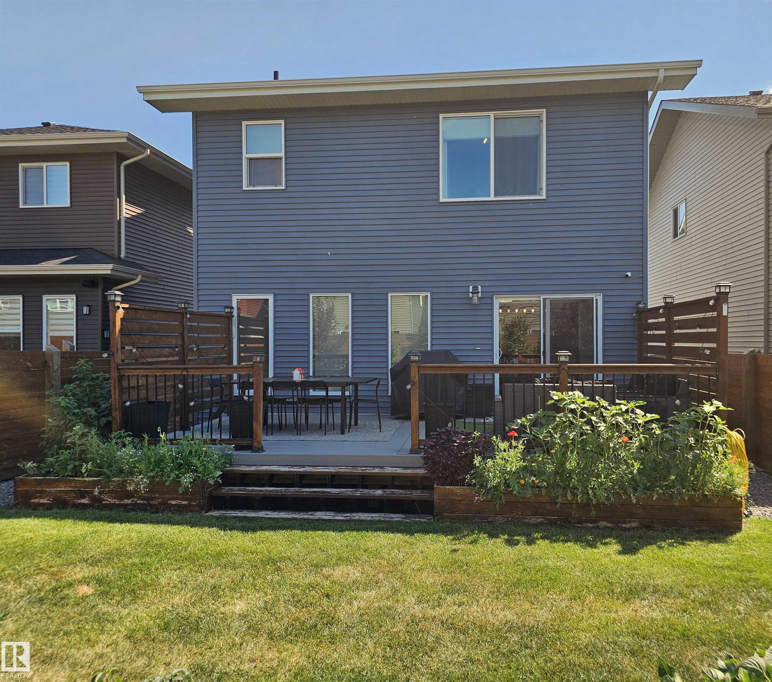 Rear exterior featuring blue horizontal siding and multiple windows - 40 Jamison Crescent, St. Albert, AB