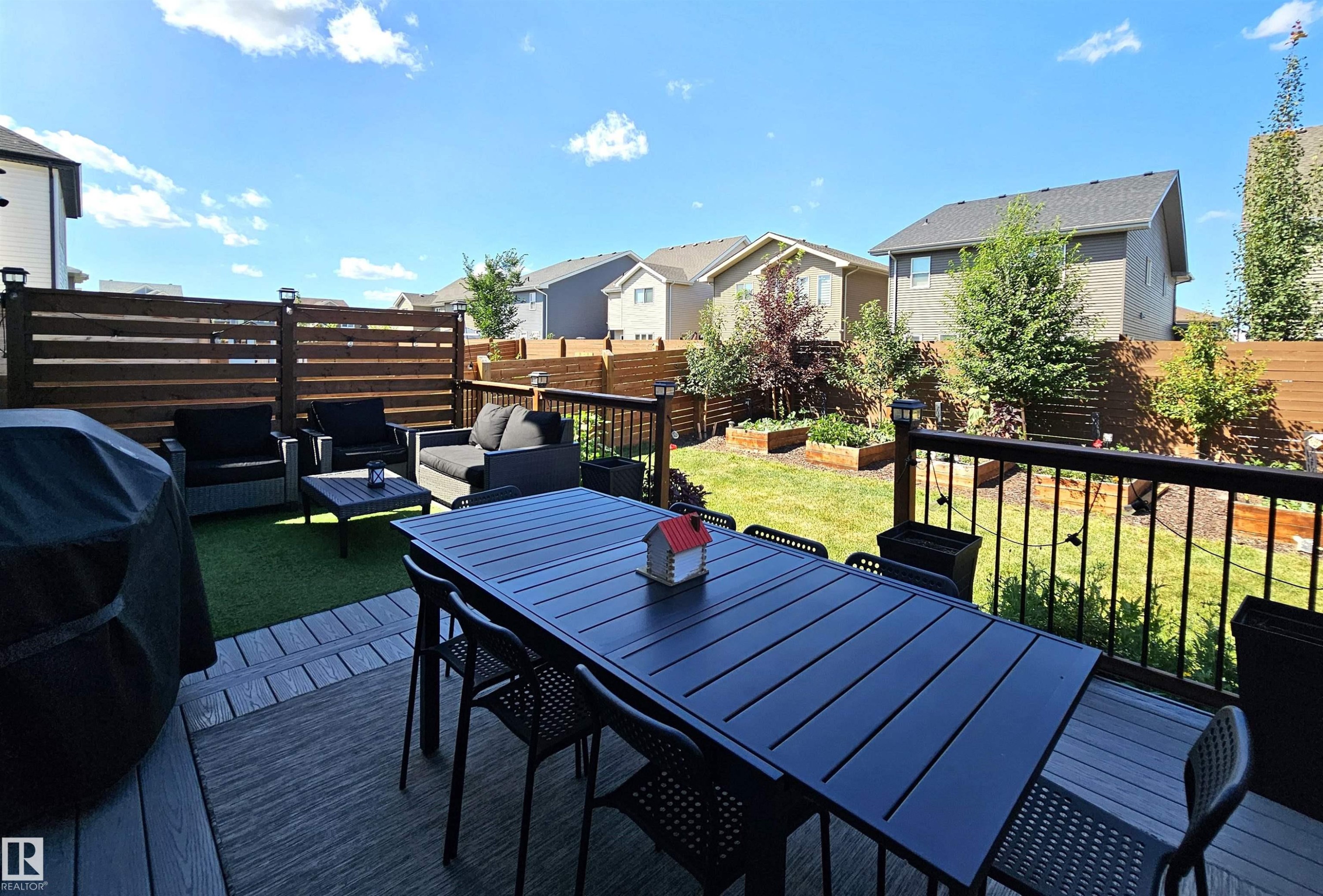Multi-level deck with composite decking, black metal railing, horizontal slatted wood privacy fence, and raised garden beds - 40 Jamison Crescent, St. Albert, AB