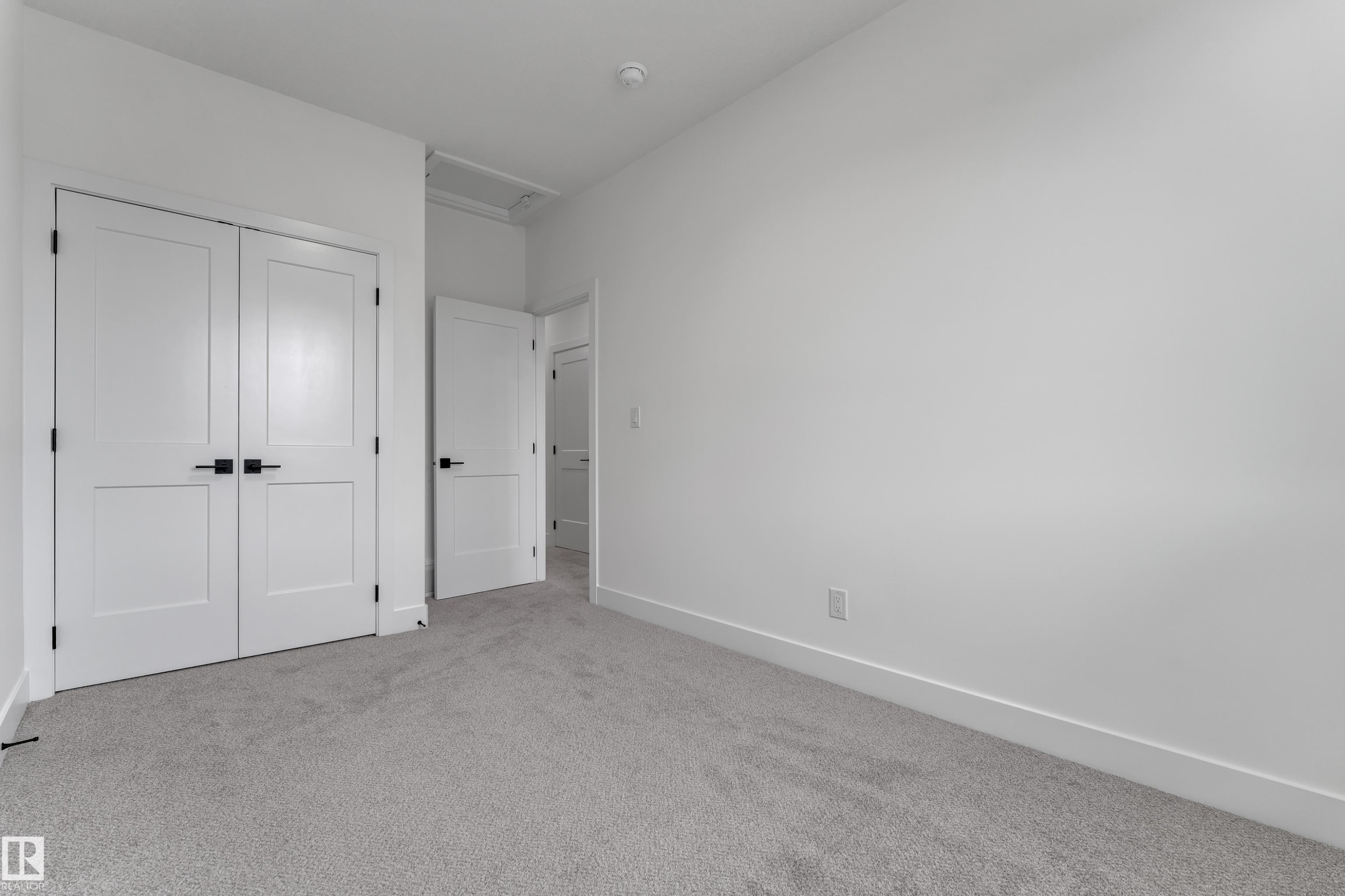 Light gray carpet flooring, white walls, white interior doors, matte black hardware, and a white ceiling - 178 Munn Way, Leduc, AB