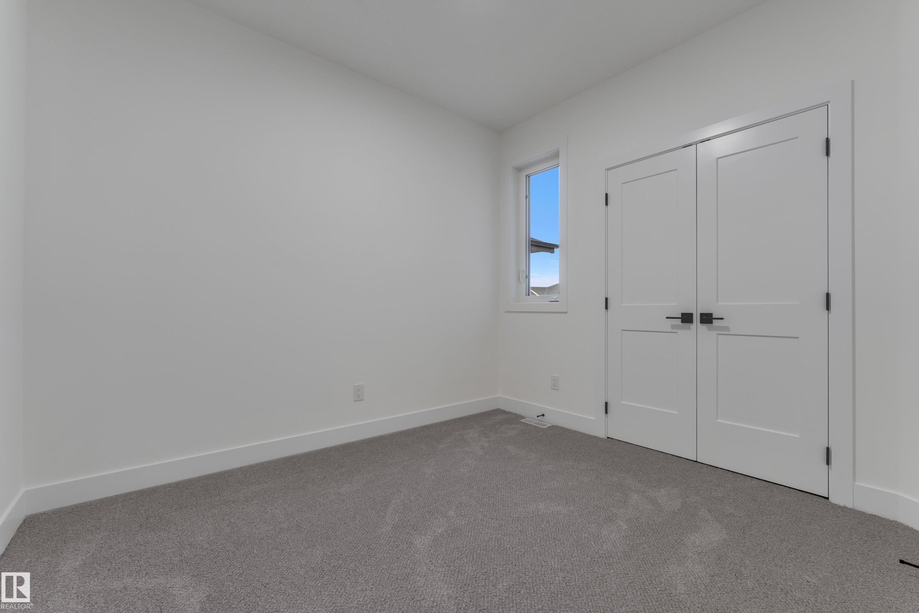 Neutral wall paint, gray carpeting, a single window, and double doors with dark hardware - 178 Munn Way, Leduc, AB