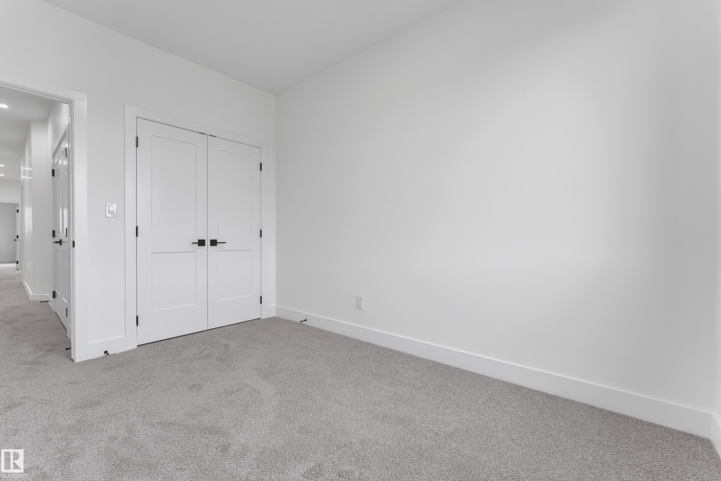 Plush grey carpeting, white double doors with matte black hardware, and crisp white walls - 178 Munn Way, Leduc, AB