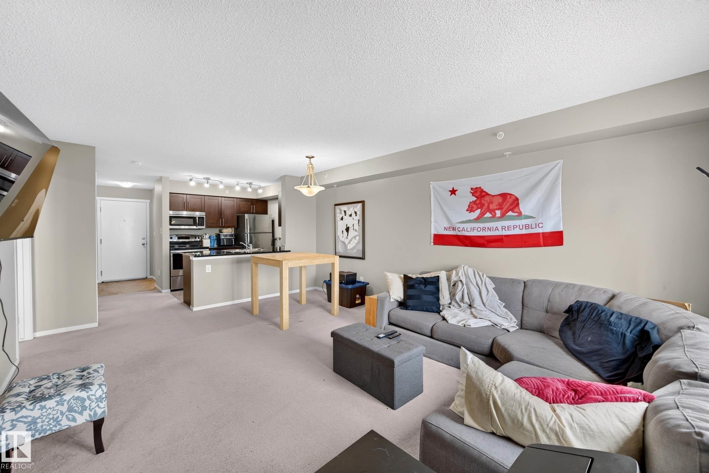 Open-concept living area with neutral wall tones and light-colored carpeting - #408 25 Element Dr, St. Albert, AB