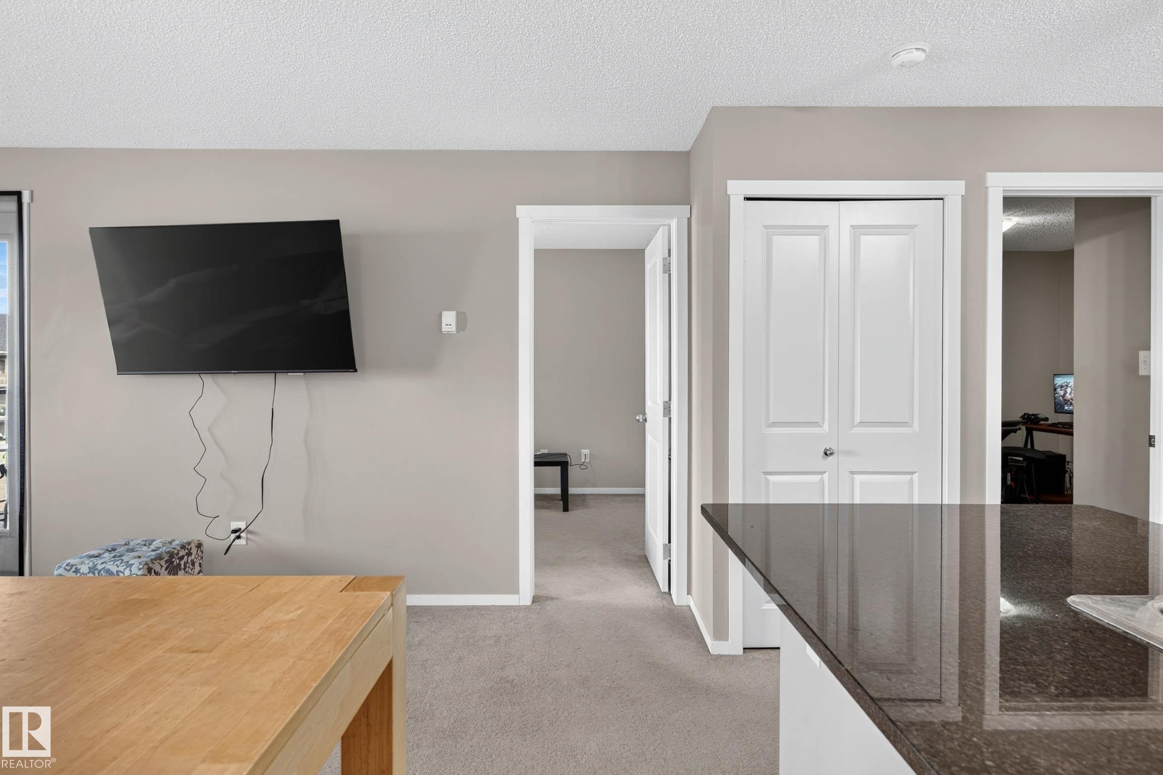 Wood-finish countertop, dark polished countertop, light neutral wall paint, light neutral carpet, and white trim throughout - #408 25 Element Dr, St. Albert, AB