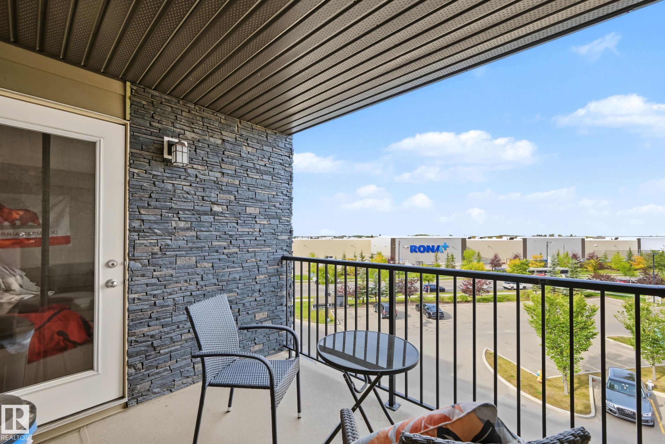 Balcony featuring a black wrought iron railing, stone veneer wall, and overhead soffit with recessed lighting - #408 25 Element Dr, St. Albert, AB