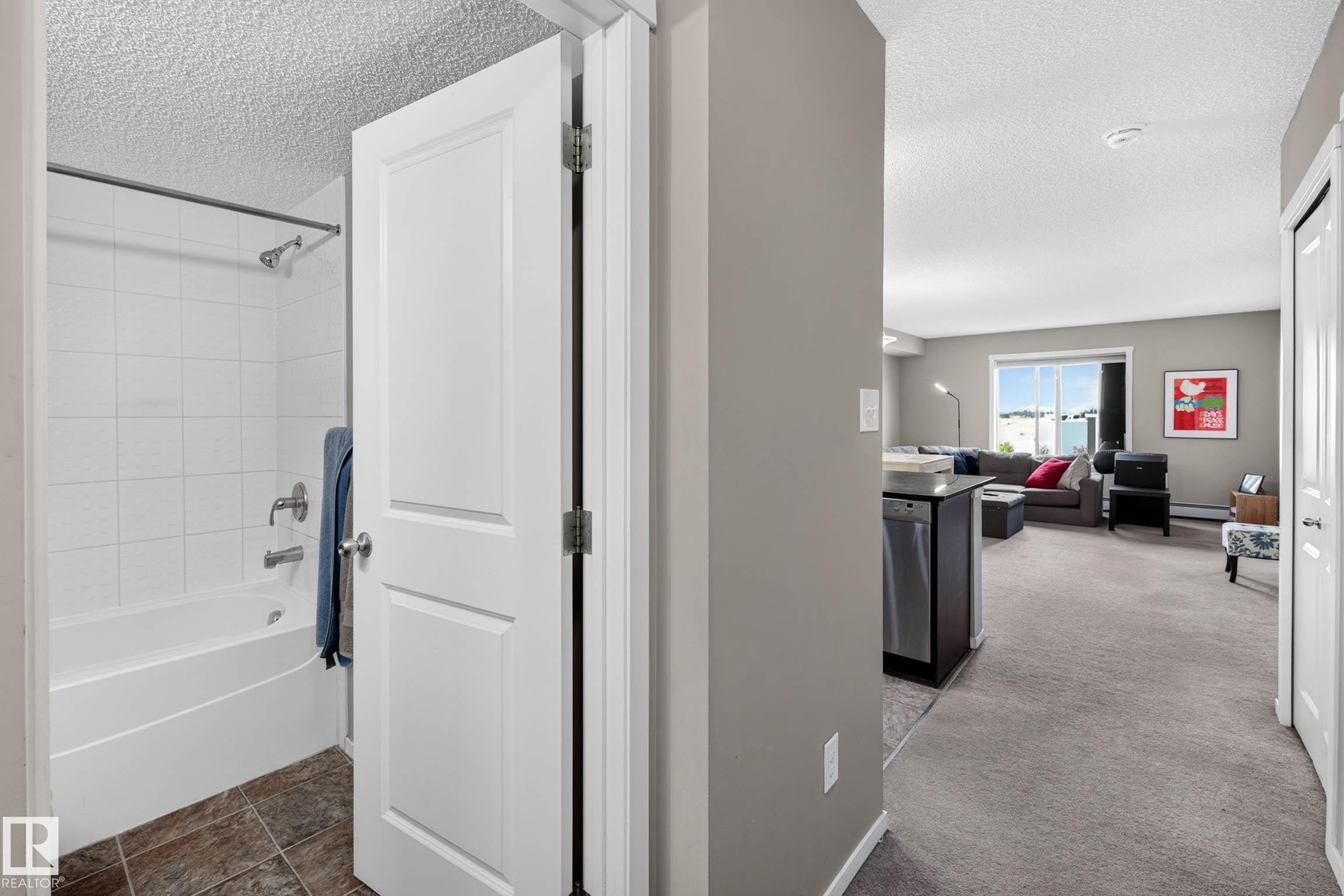 Recessed bathtub with white subway tile surround, chrome shower head, and tile flooring - #408 25 Element Dr, St. Albert, AB
