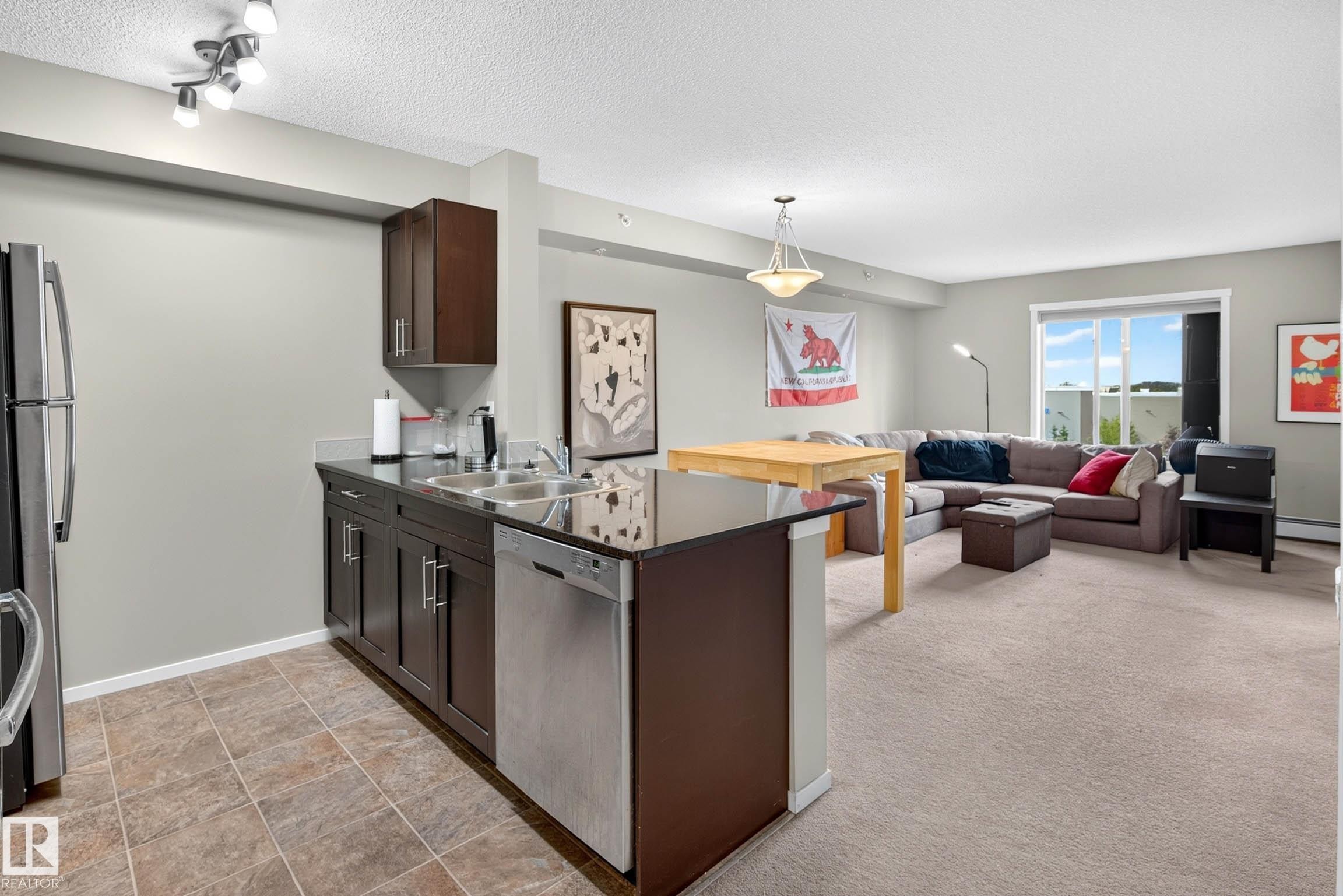 Kitchen with dark wood cabinetry, stainless steel appliances, and a double basin sink - #408 25 Element Dr, St. Albert, AB