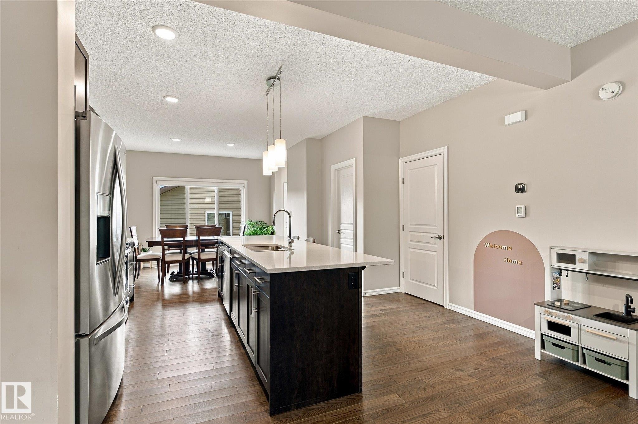 Hardwood-finish flooring, recessed lighting, and a kitchen island with pendant lighting and an undermount sink - 21935 91 Avenue Nw, Edmonton, AB