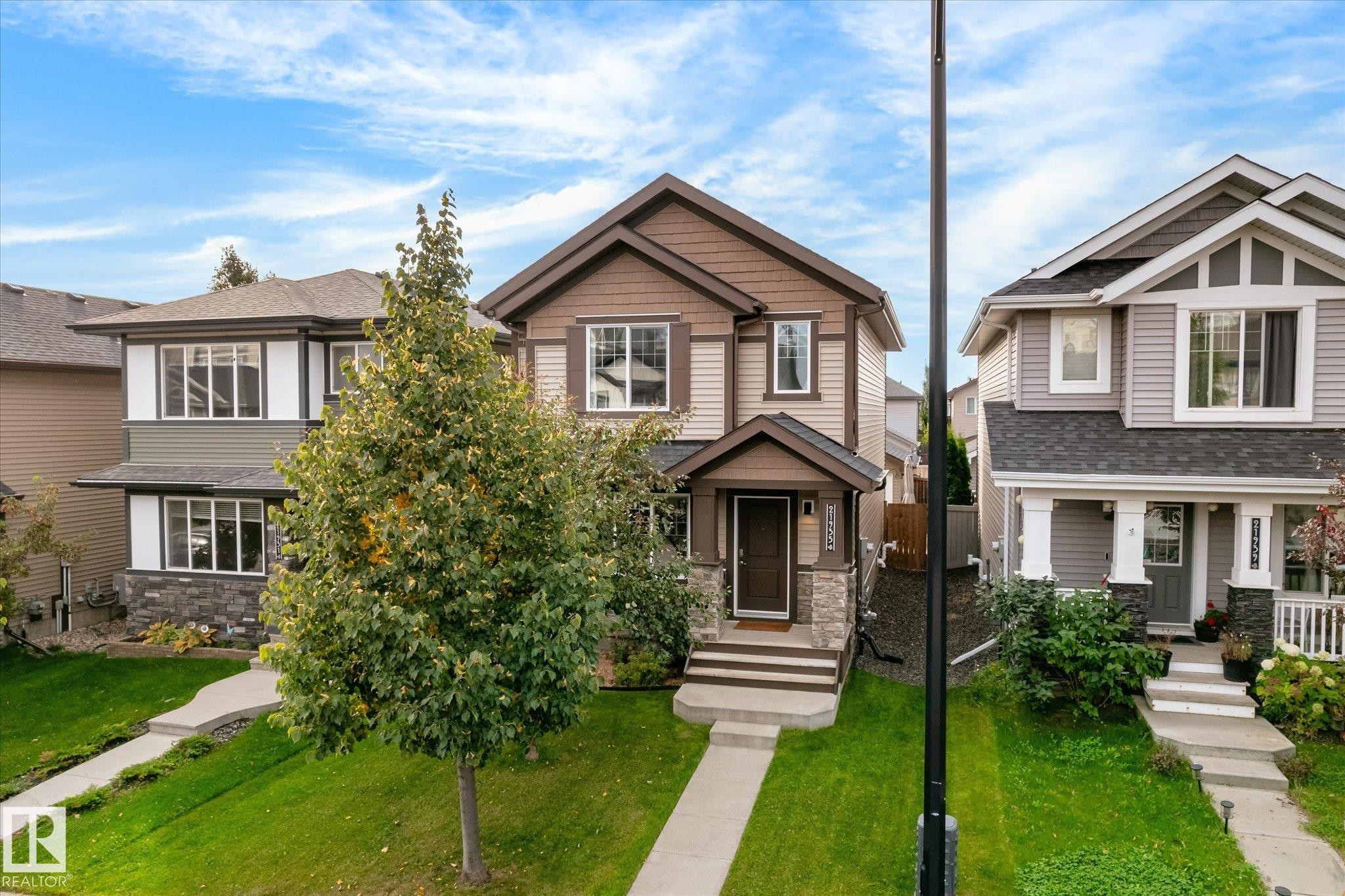 Two-story brown and tan exterior with stone accents, a covered front entry, and a concrete walkway - 21935 91 Avenue Nw, Edmonton, AB