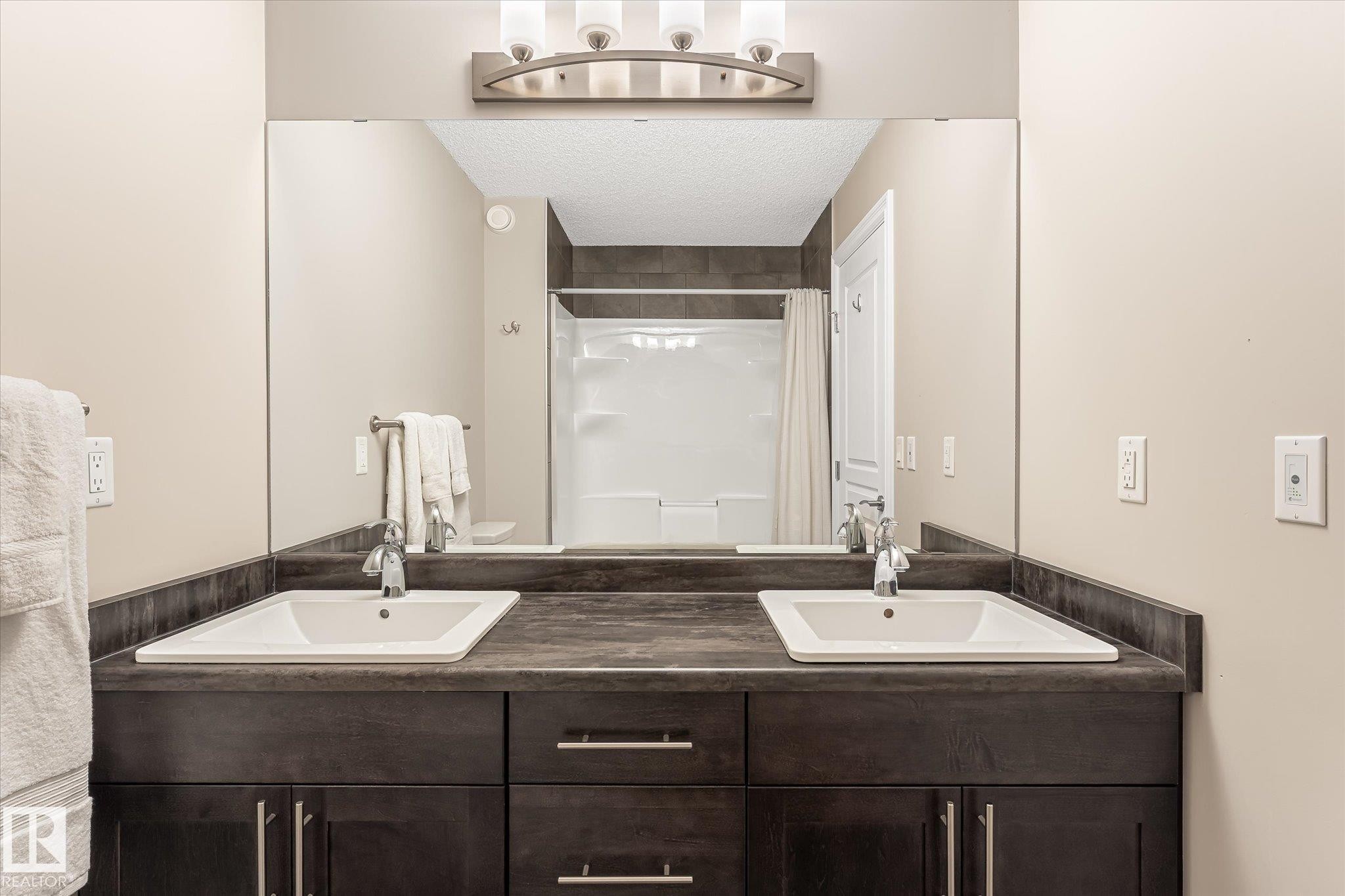 Double vanity with integrated rectangular sinks, dark wood-finish cabinetry, and brushed nickel hardware - 21935 91 Avenue Nw, Edmonton, AB