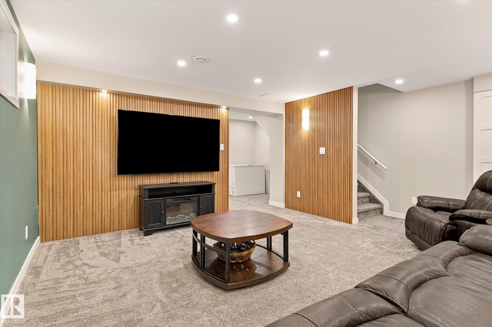 Wood-slat accent wall, recessed ceiling lighting, wall-mounted light fixtures, carpeted flooring, and built-in media console - 21935 91 Avenue Nw, Edmonton, AB