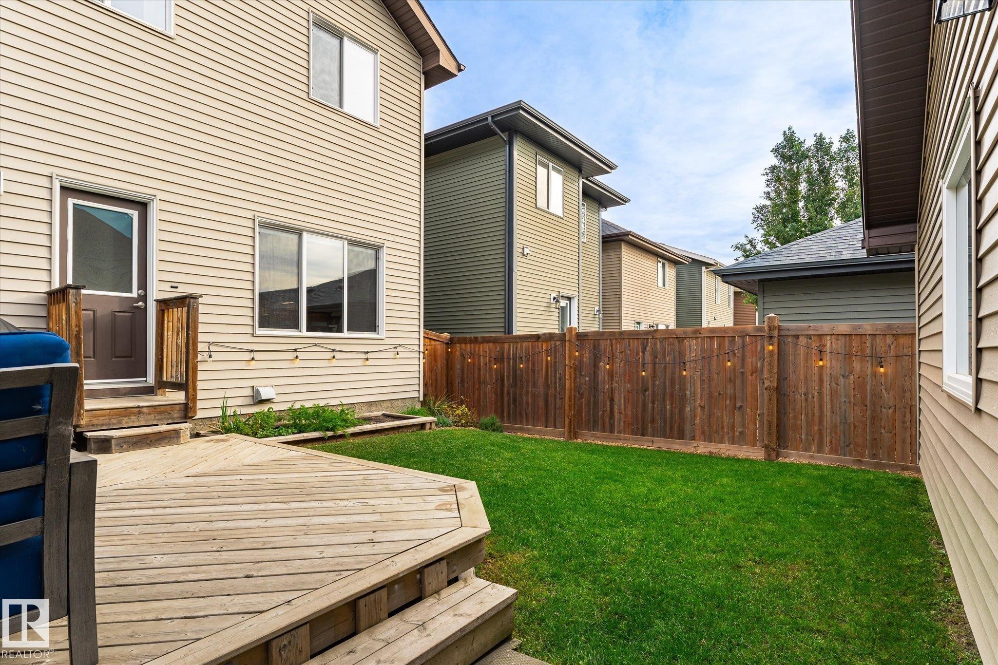 Expansive wooden deck with steps, leading to a vibrant green lawn - 21935 91 Avenue Nw, Edmonton, AB