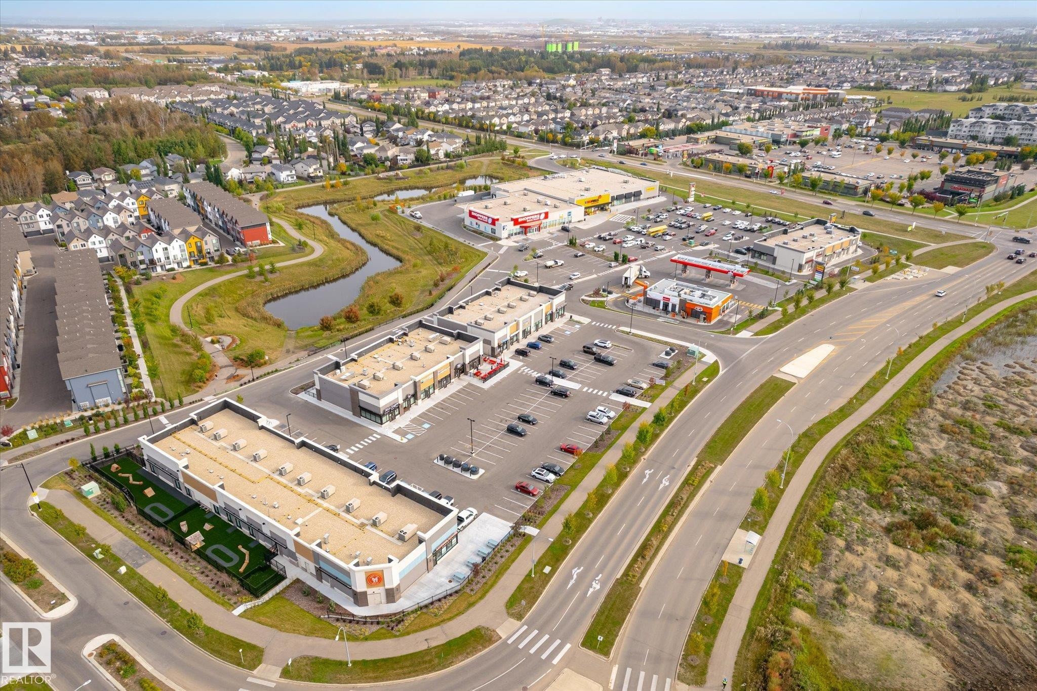 Mixed-use development featuring commercial retail spaces, surface parking, and residential townhomes - 21935 91 Avenue Nw, Edmonton, AB