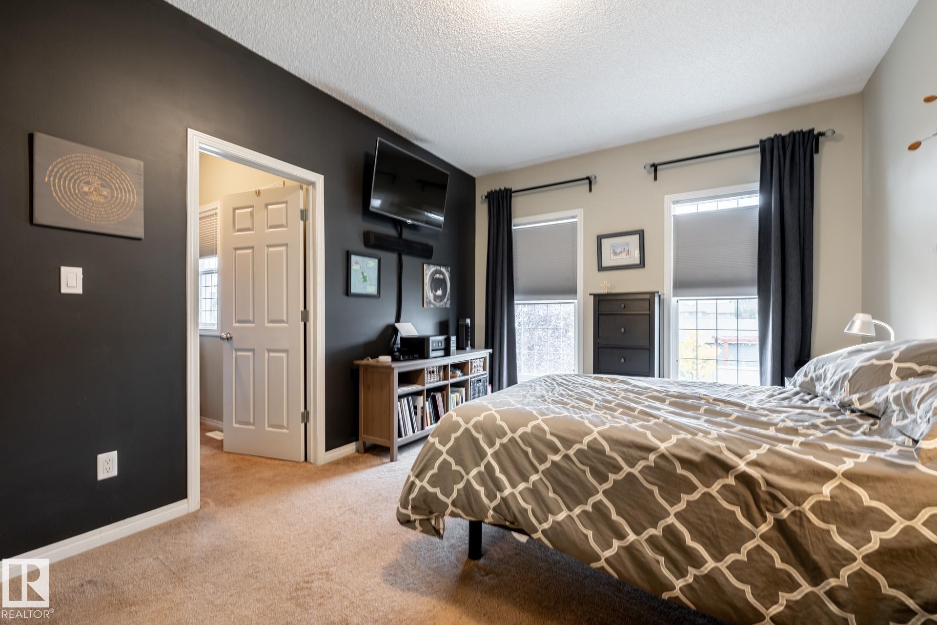 Room featuring an accent wall, two windows with dual-track rod hardware, wall-to-wall carpeting, and a six-panel interior door - 2093 Chalmers Way Sw, Edmonton, AB