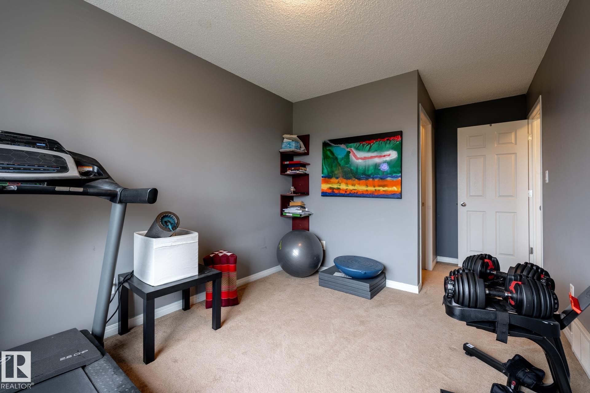 Room featuring neutral-toned walls, neutral carpeting, and a built-in corner shelving unit - 2093 Chalmers Way Sw, Edmonton, AB