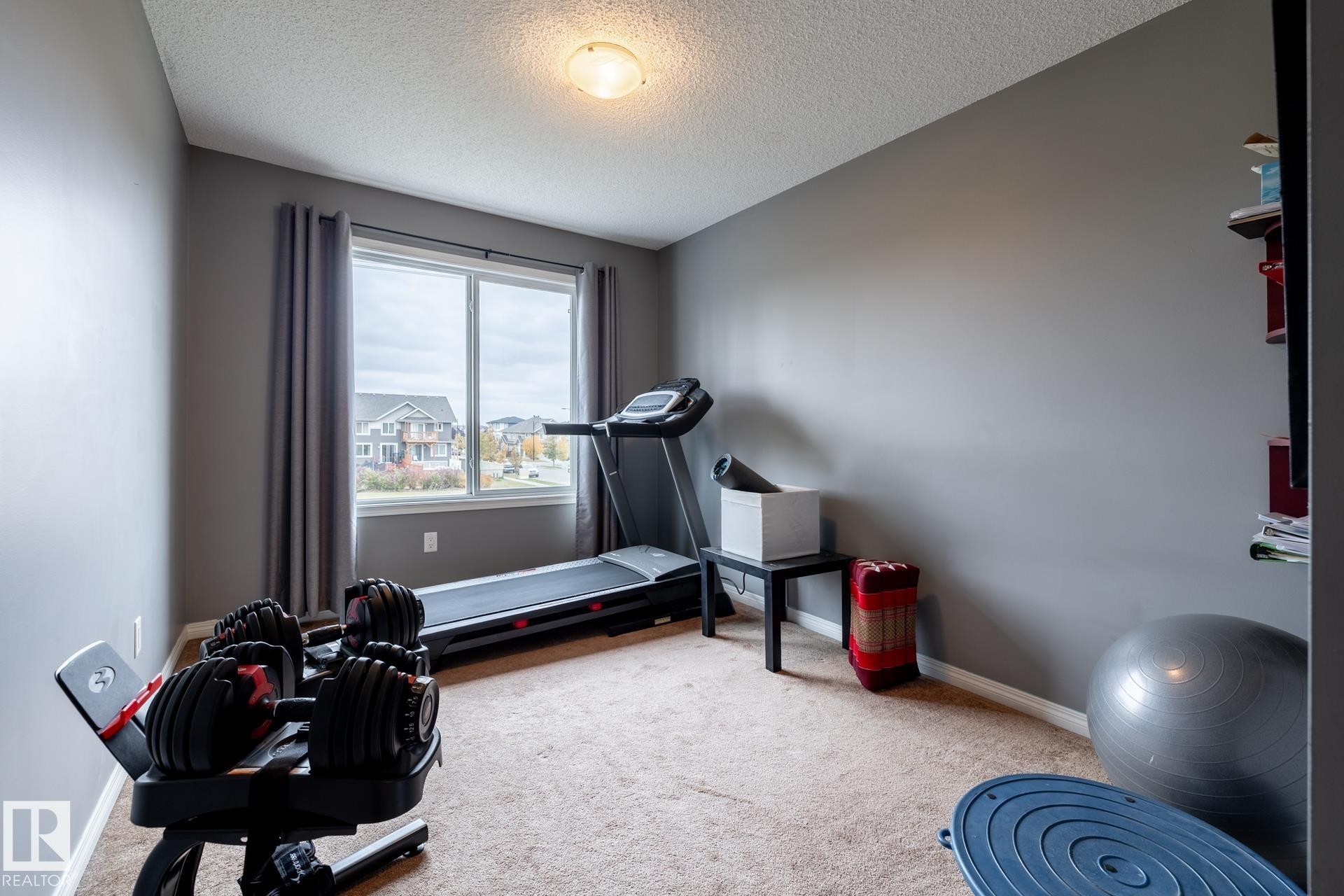 Room featuring neutral-toned walls, carpeting, a large window with natural light, and a central ceiling-mounted light fixture - 2093 Chalmers Way Sw, Edmonton, AB