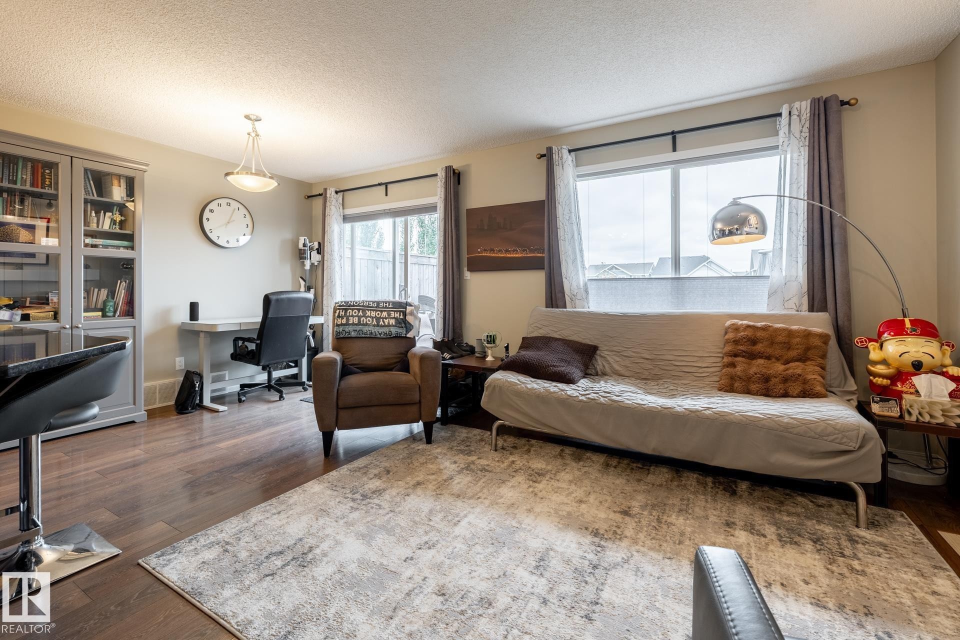 Wood-finish flooring, built-in display cabinetry, and large windows with integrated curtain rods - 2093 Chalmers Way Sw, Edmonton, AB