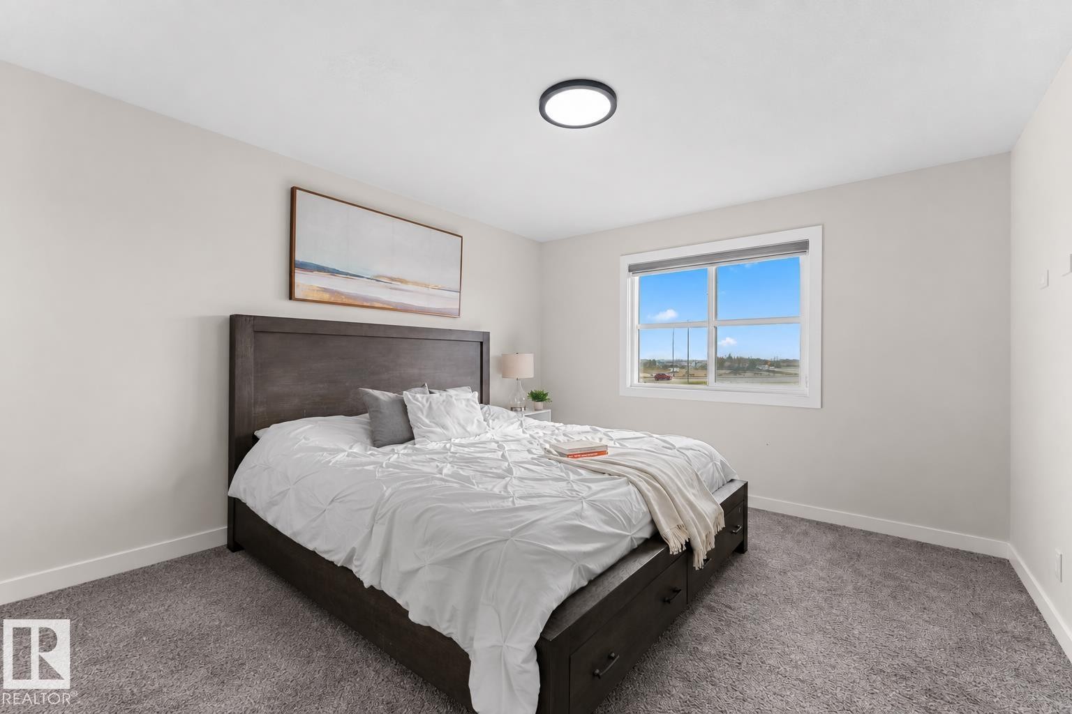 Spacious room featuring neutral wall tones, a large window with white trim, and a flush-mount ceiling light - 1142 Goldfinch Crescent Nw, Edmonton, AB
