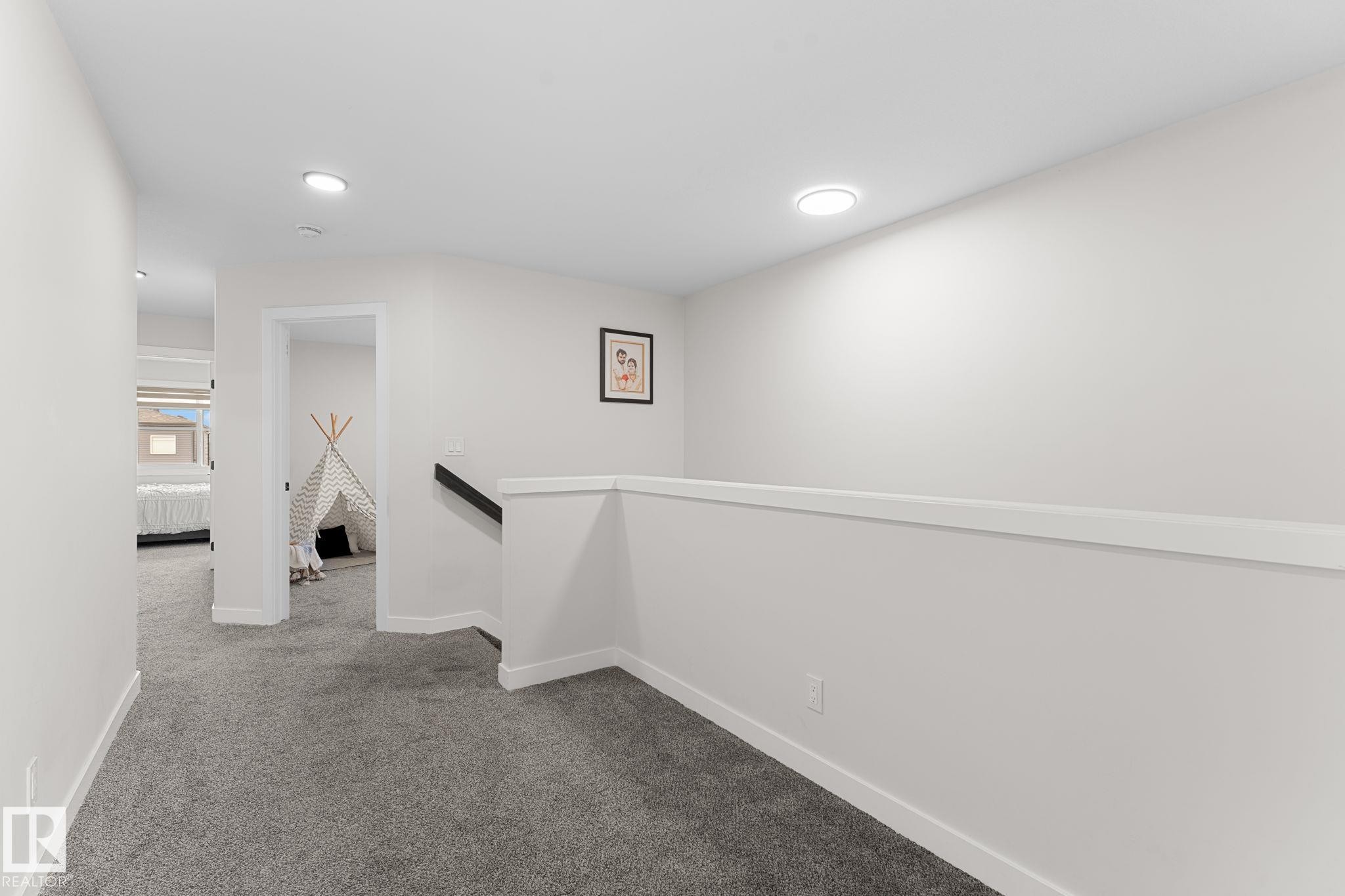 Recessed ceiling lighting illuminates the gray carpeted hallway with white painted walls - 1142 Goldfinch Crescent Nw, Edmonton, AB