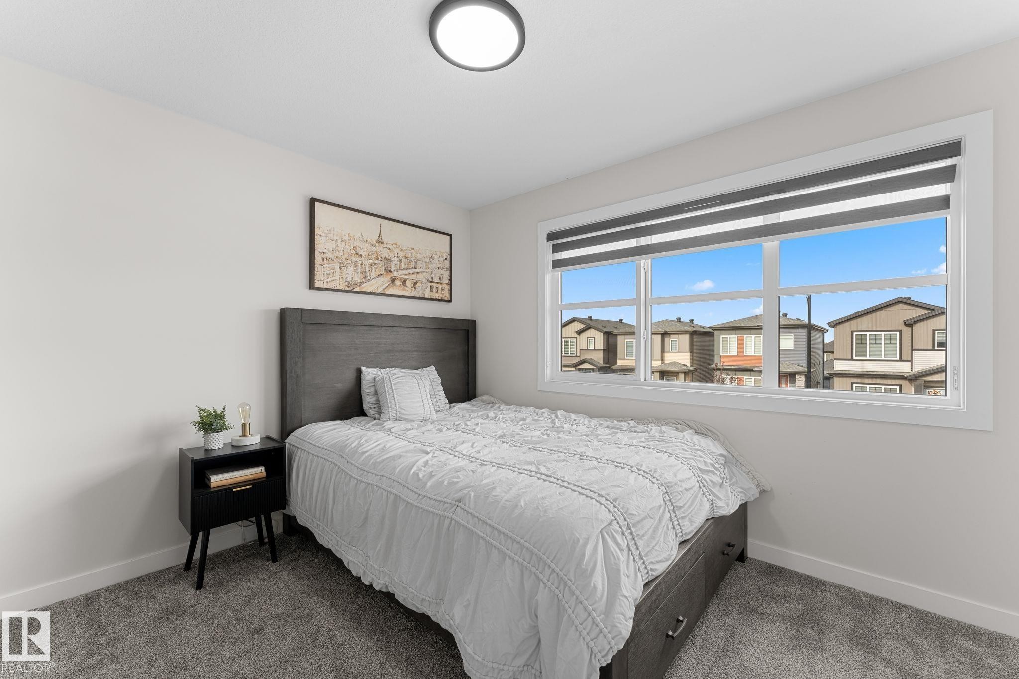 Wall-to-wall carpeting, a large window with roller shades, and a flush-mount ceiling light - 1142 Goldfinch Crescent Nw, Edmonton, AB