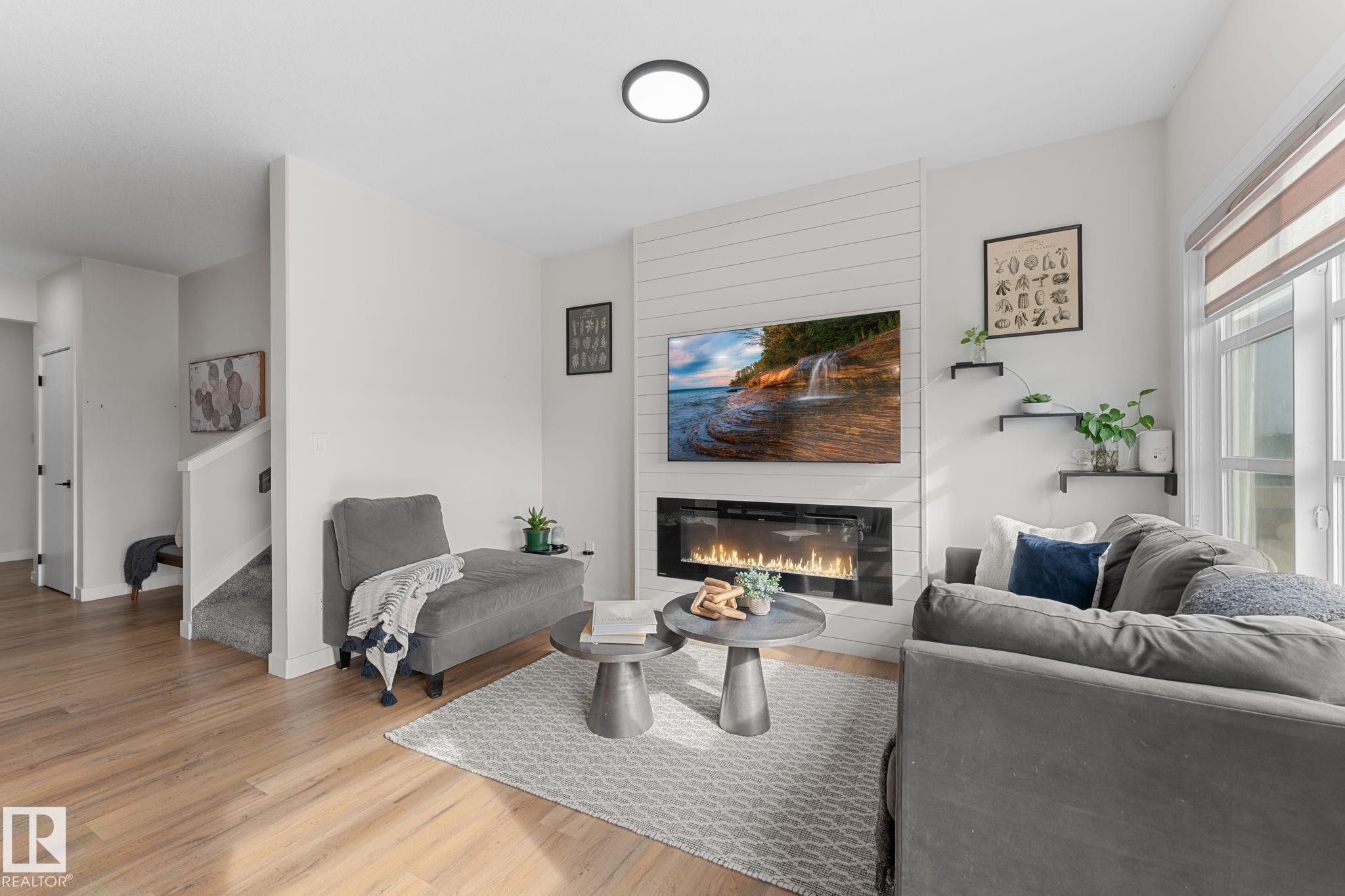 Wood-finish flooring, white walls, and an electric fireplace with shiplap-style surround - 1142 Goldfinch Crescent Nw, Edmonton, AB