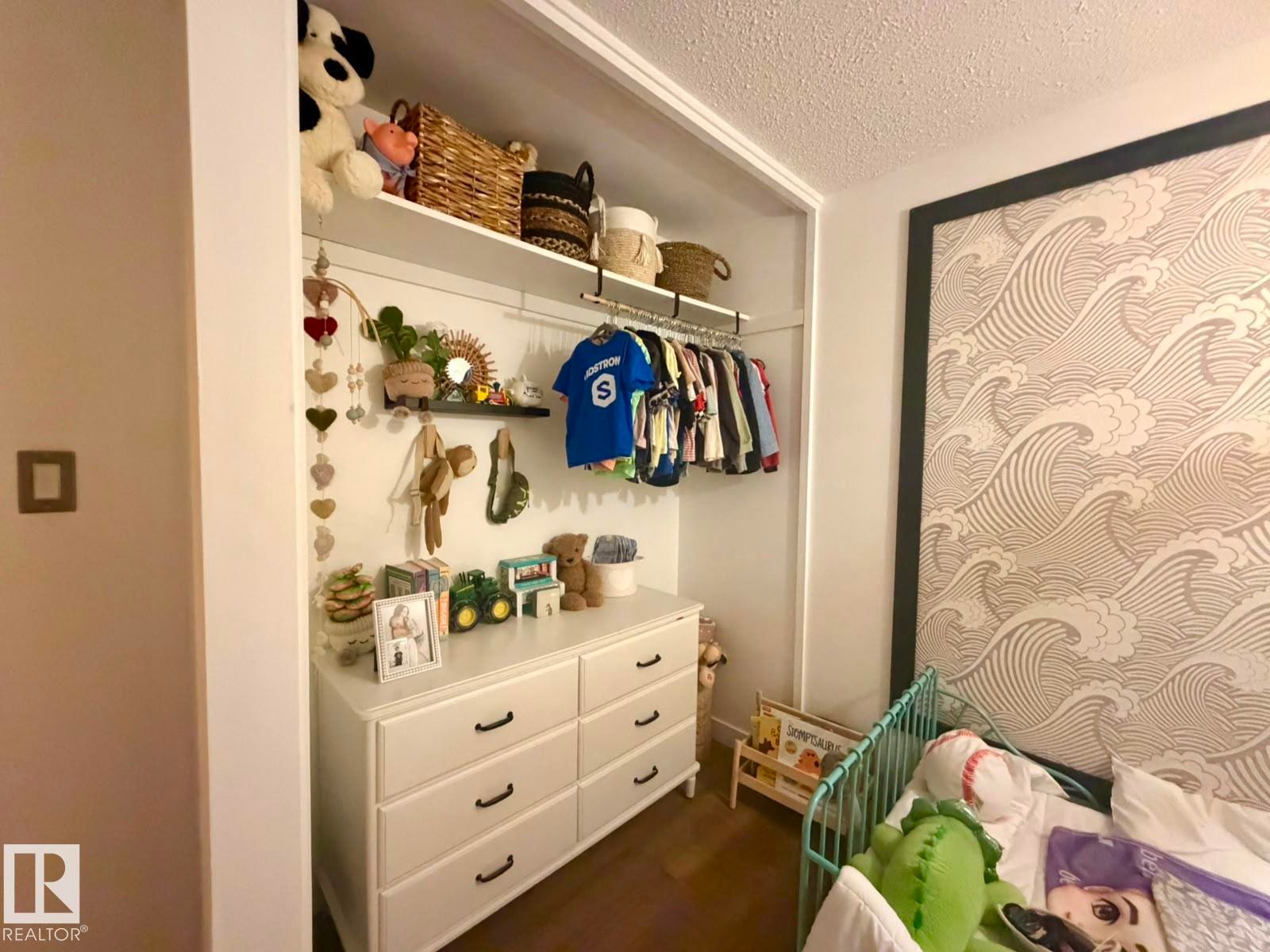 Built-in closet system with open shelving and clothing rod, white six-drawer dresser with black hardware, and patterned accent wall - 5 Gilmore Crescent, St. Albert, AB