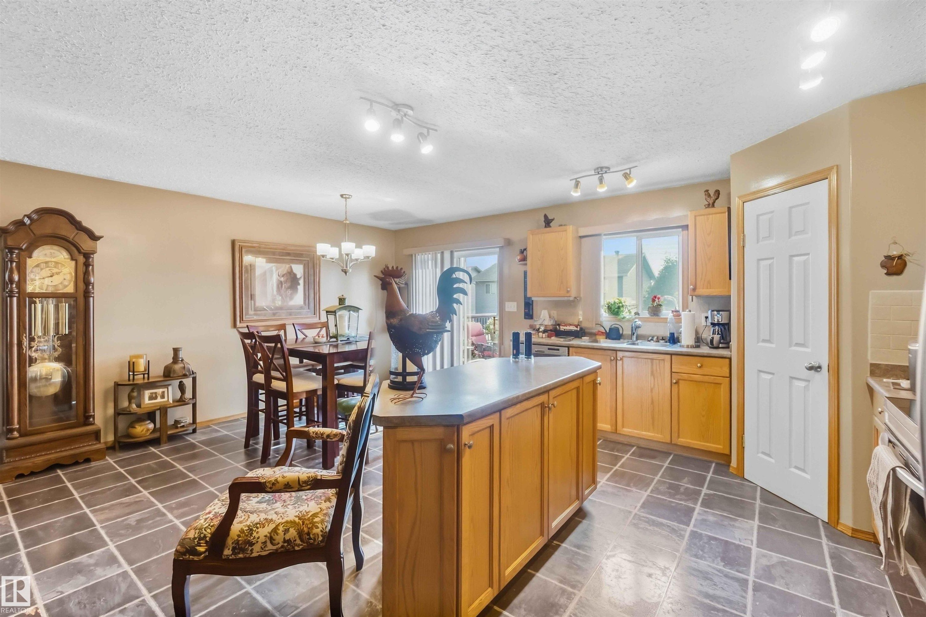 Open-concept interior featuring large-format tile flooring, recessed and flush-mount lighting, and kitchen cabinetry with a wood finish - 497 Kananaskis Drive, Devon, AB