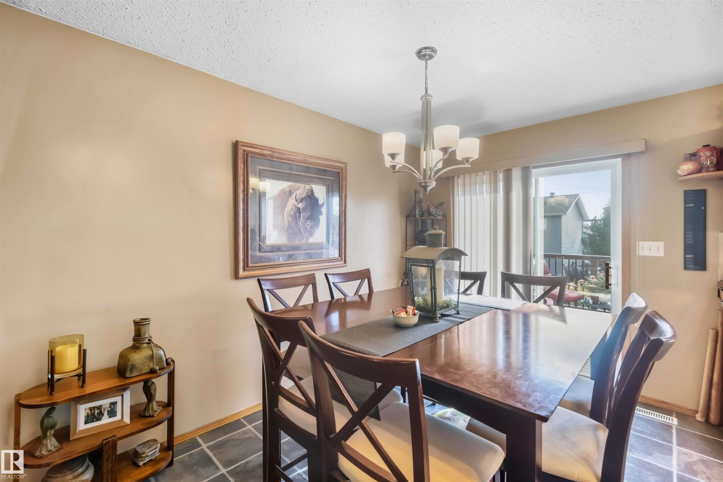 Kitchen featuring light-finish cabinetry, a center island with a solid surface countertop, stainless steel appliances, and slate-finish tile flooring - 497 Kananaskis Drive, Devon, AB